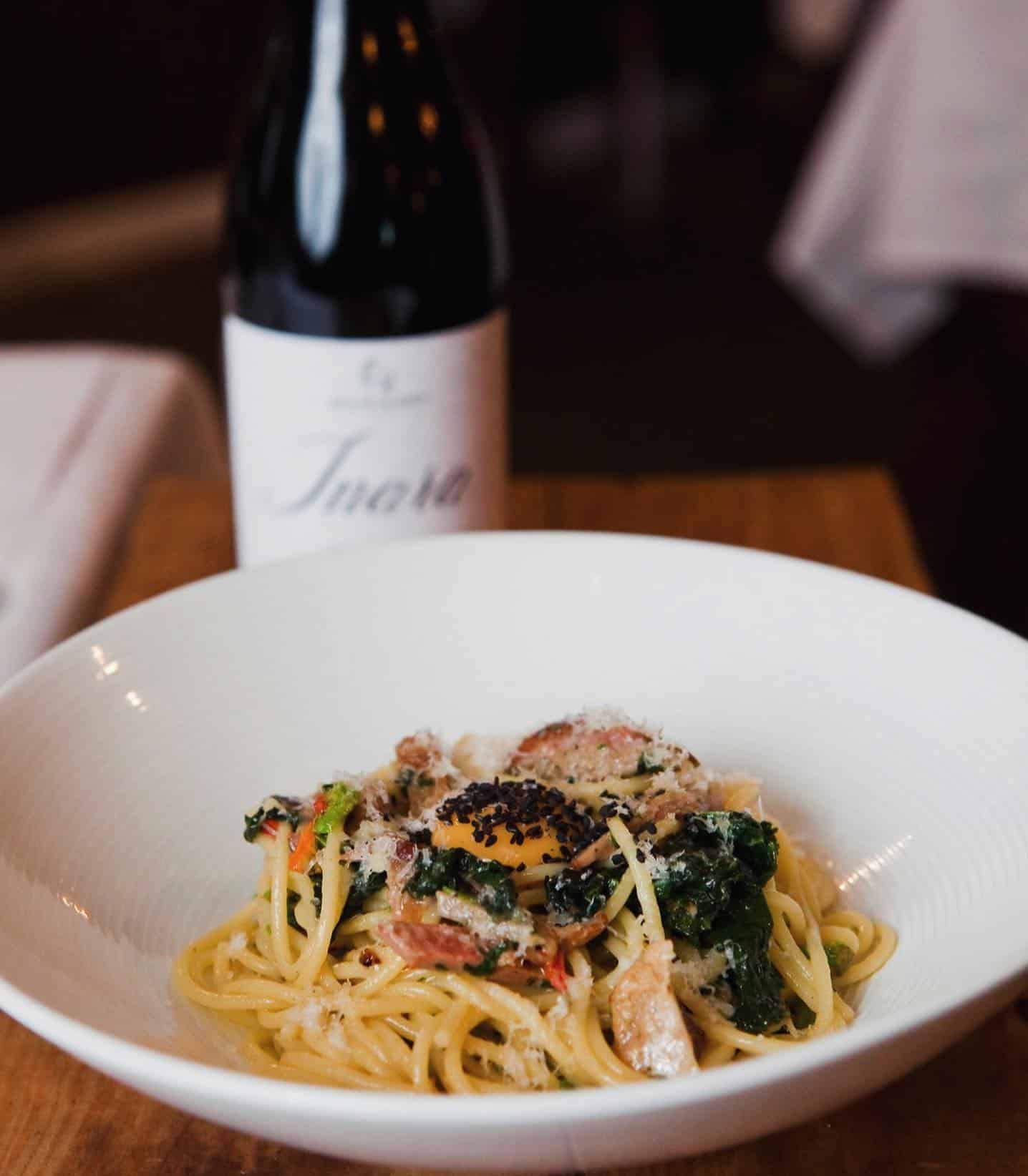A Bowl of Spaghetti With a Bottle of Wine in the Background — Onesta Cucina in Bowral, NSW