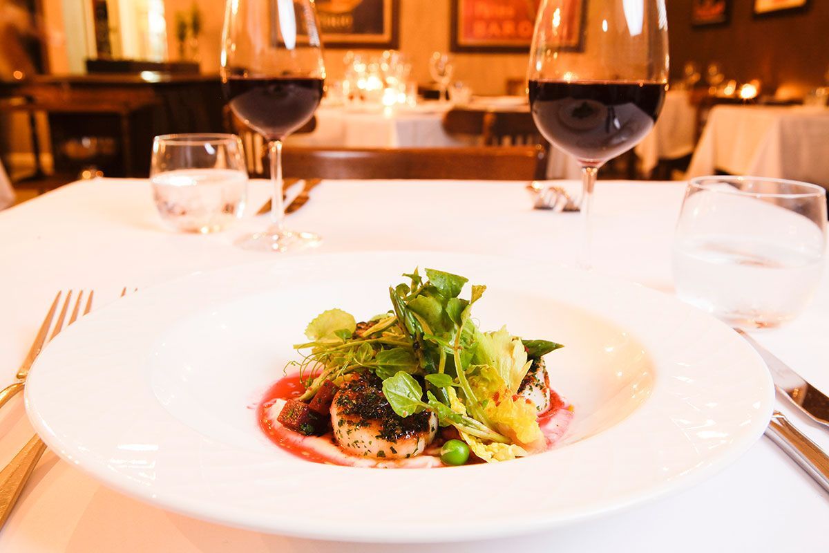 A Plate of Food and Two Glasses of Wine on a Table in a Restaurant — Onesta Cucina in Bowral, NSW