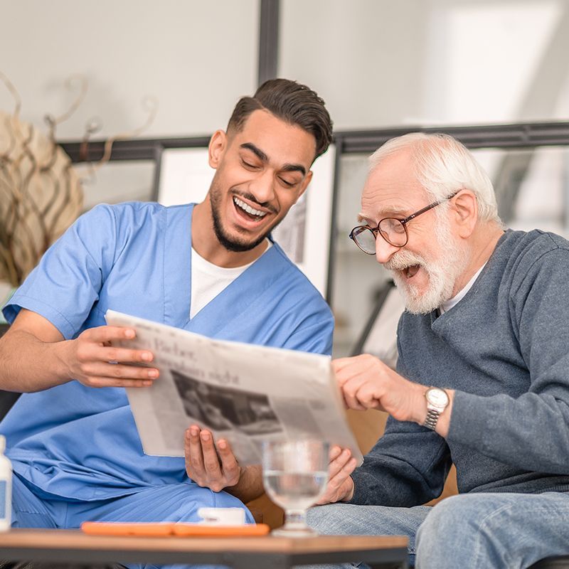 Helper Reading With Elderly Man Helper Reading With Elderly Man