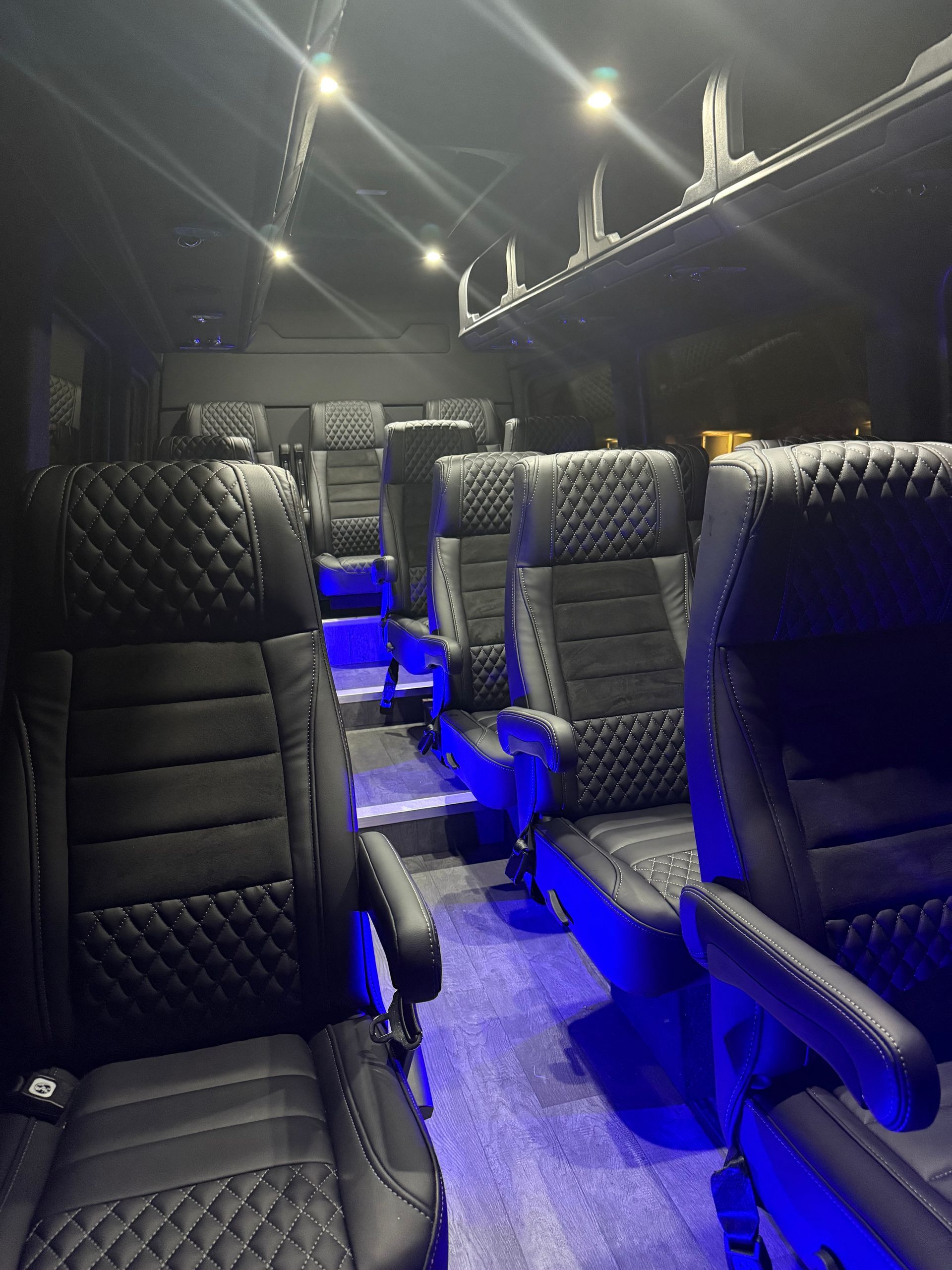 Empty luxury van interior with black quilted seats and blue floor lighting