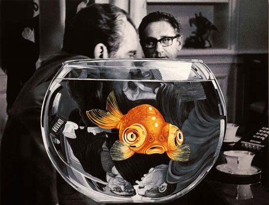 A man is looking at a goldfish in a bowl.
