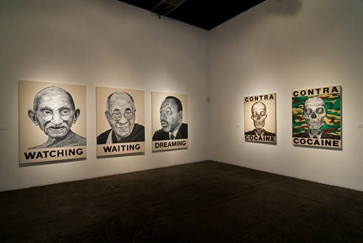 A row of paintings on a wall with one that says `` watching ''