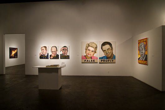 A room with a lot of paintings on the wall and a table.