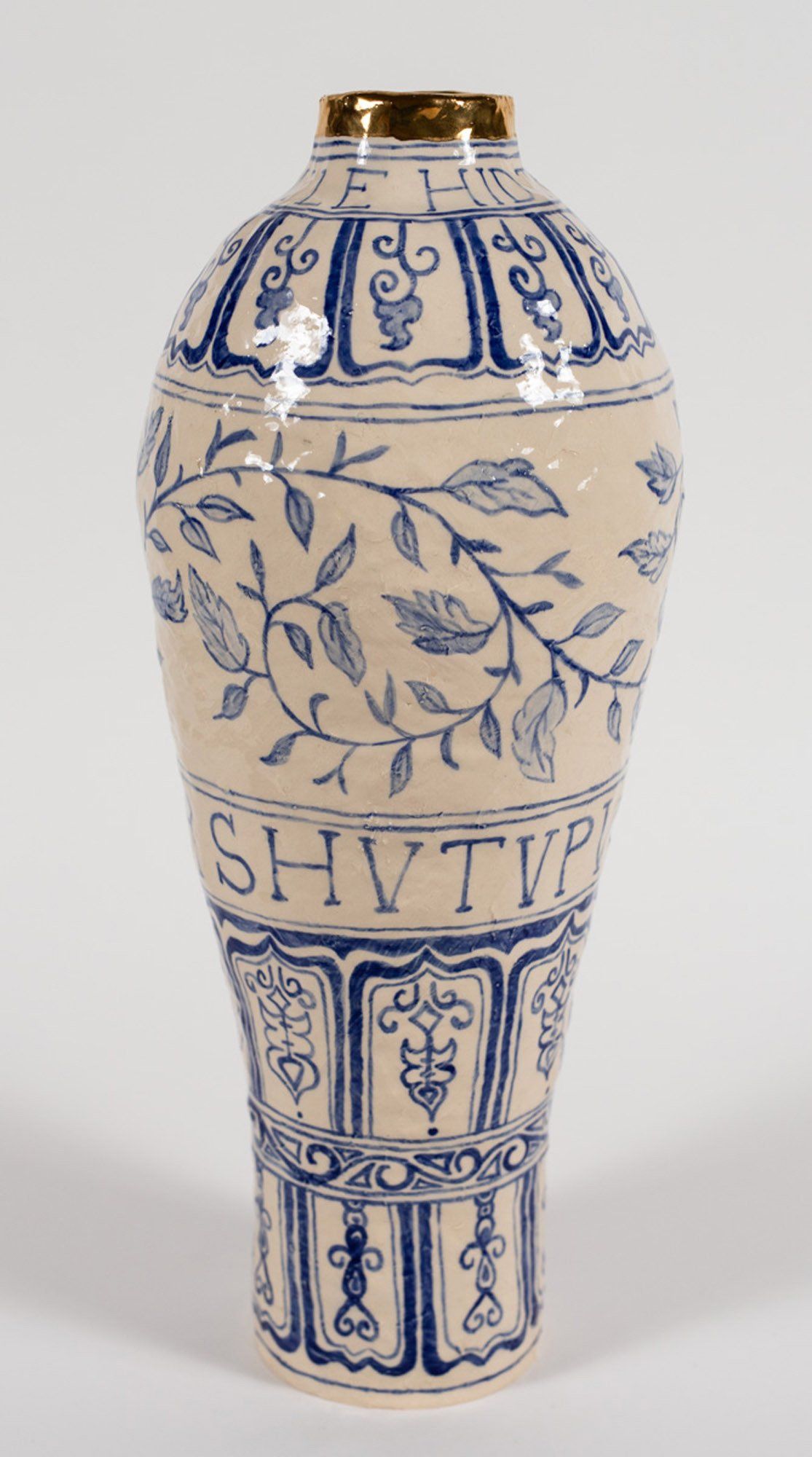 A white vase with blue vines and letters on it.