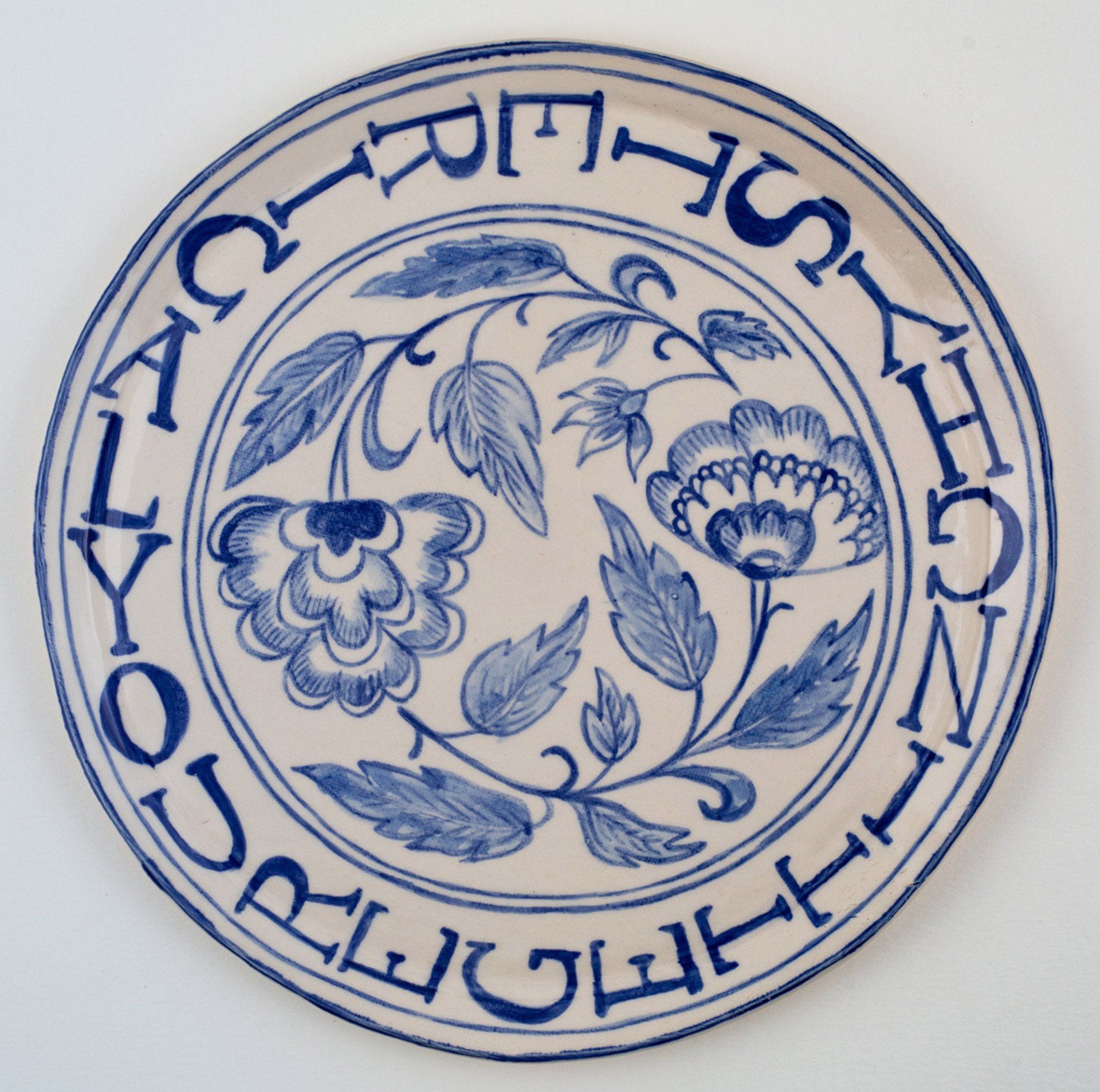 A blue and white plate with a floral design and the words our lady