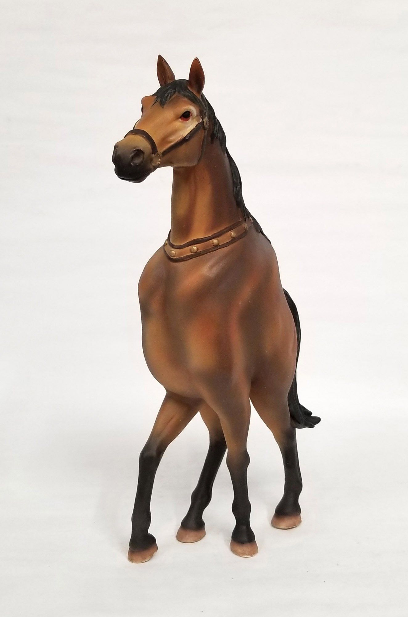 A brown horse is standing on a white surface