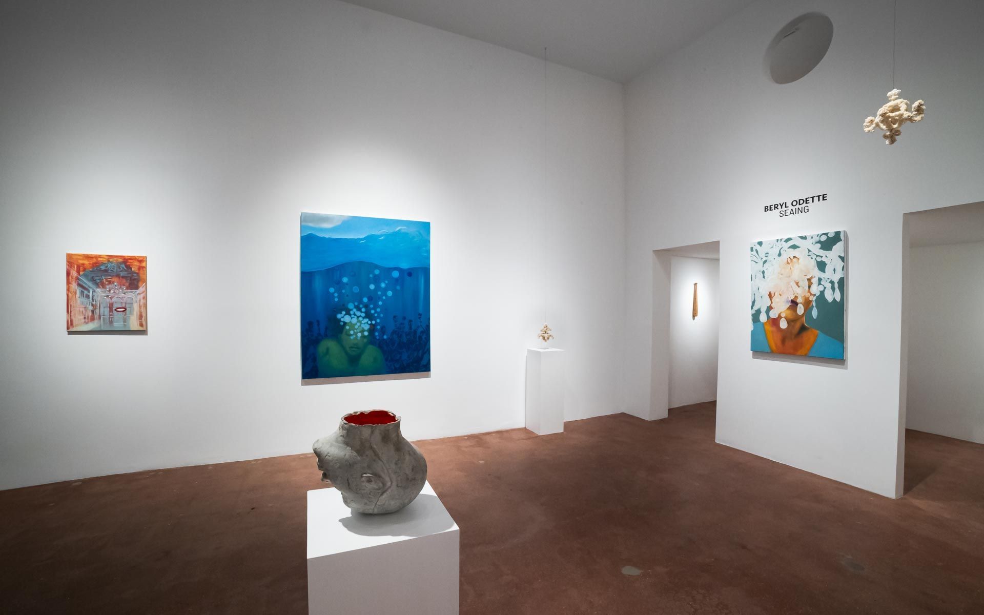 Portrait painting of a woman with white hair at left, a ceramic piece on a pedestal, and a red ladder beside a painting of a figure at right. Installation view, Beryl Odette: Seaing, Track 16.