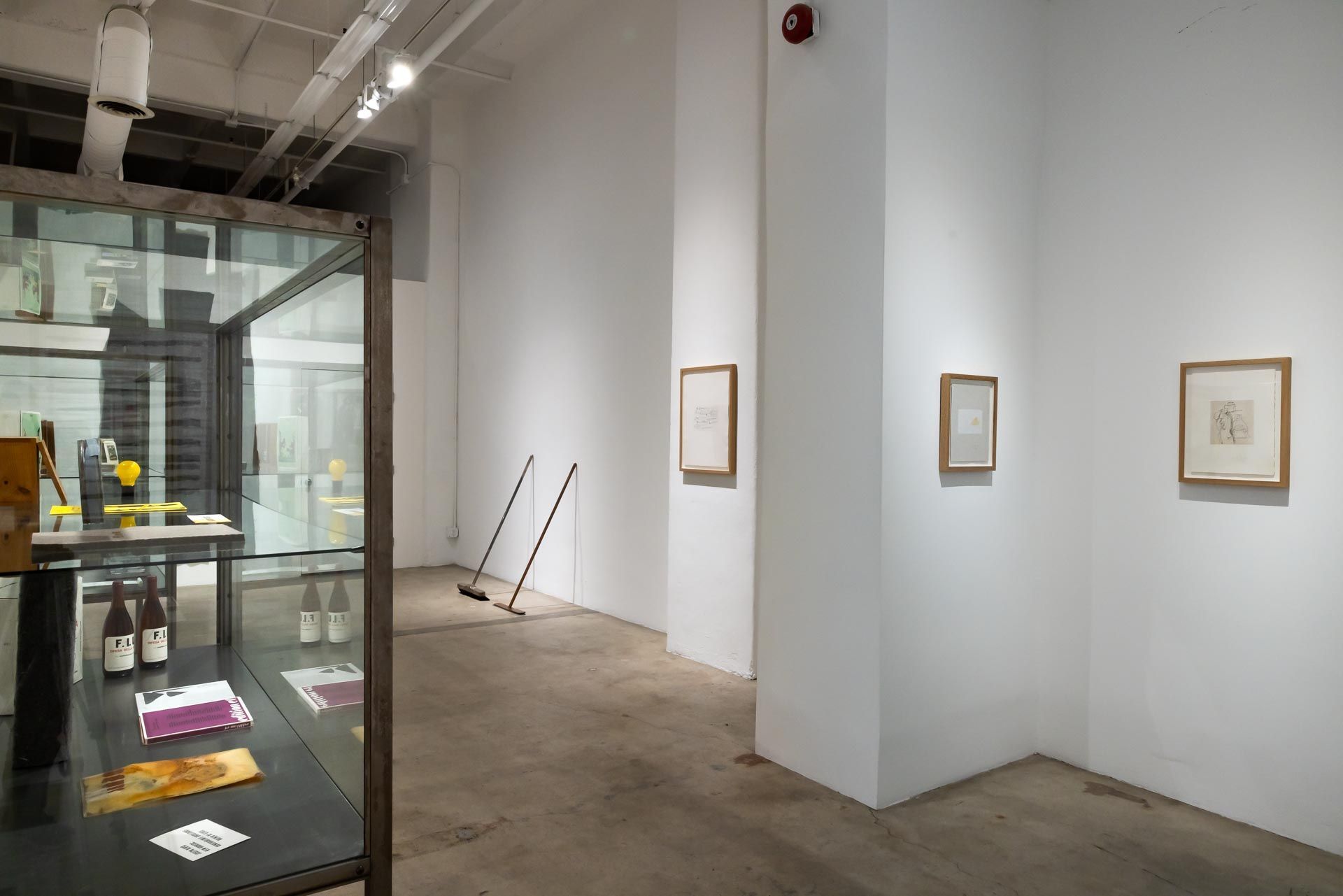 Minimalist art gallery with framed drawings on white walls and a glass display case in the foreground. TRACK 16 | DOWNTOWN LA art exhibition and retrospective of JOSEPH BEUYS titled POTENTIAL GOODS. Sculpture, mixed media and drawings.