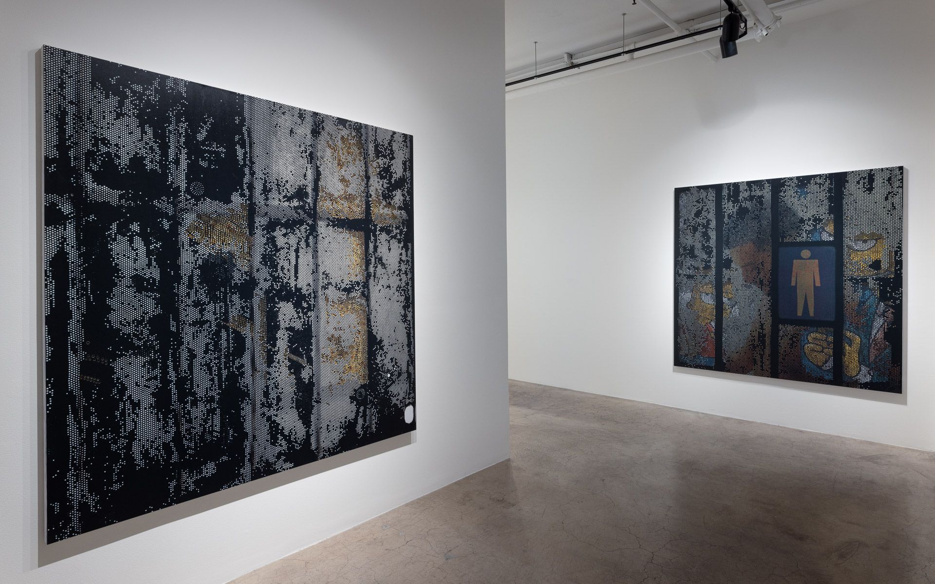 Large dark perforated panel at left and a second dark panel with a gold standing-figure pictogram on the far wall. Installation view, David Daigle: Trypophobic Panopticons, Track 16.