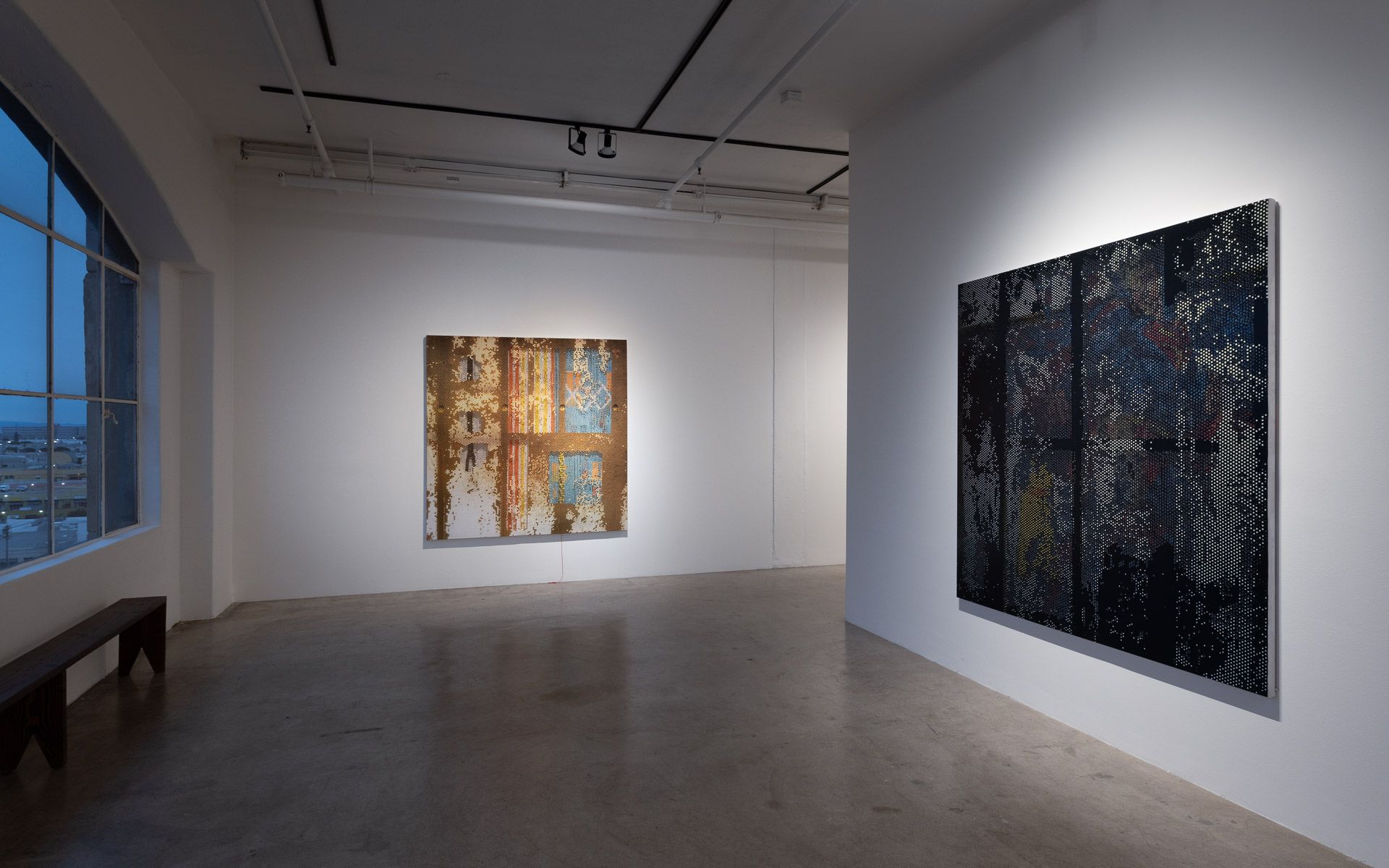 A large empty room with two paintings on the wall.