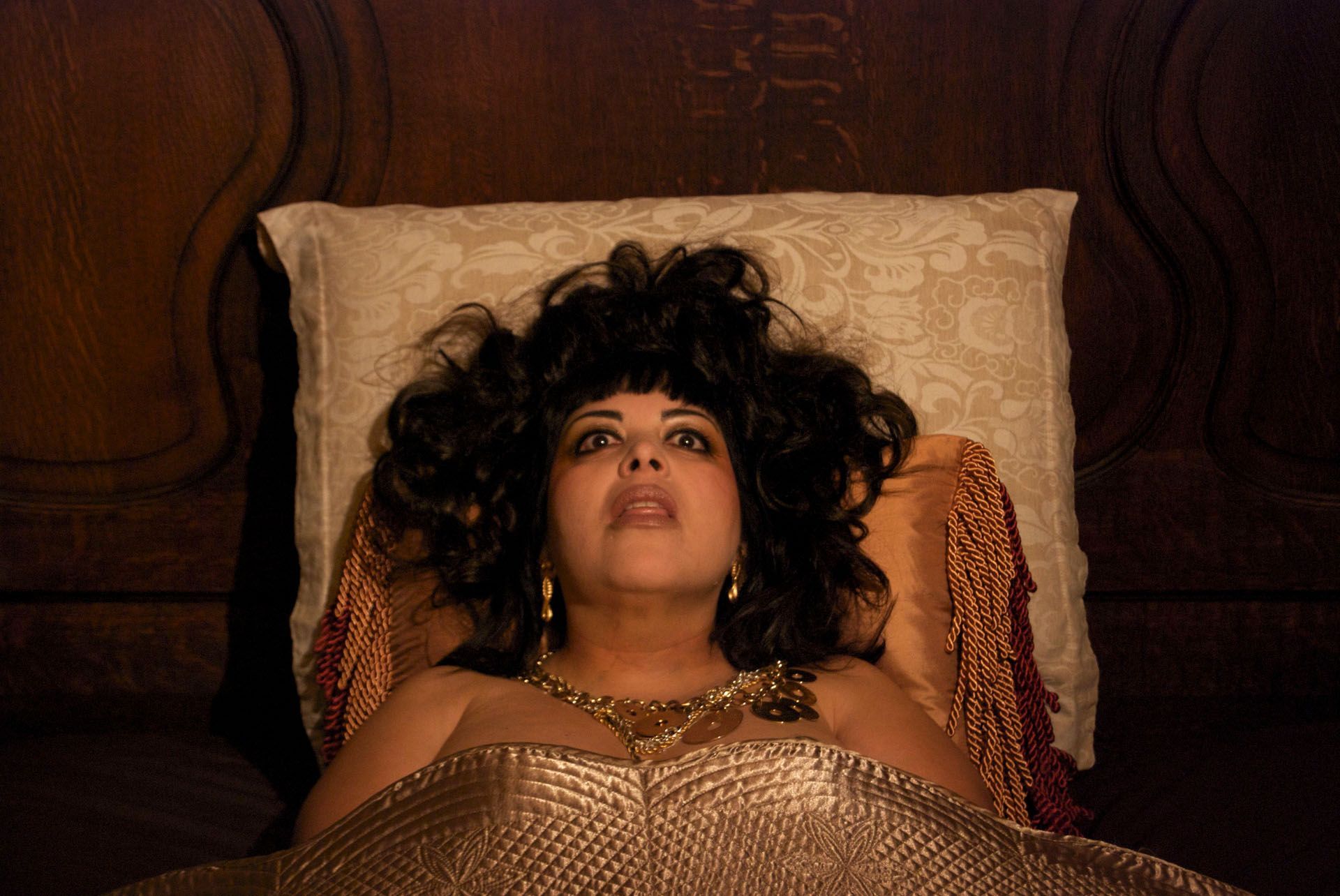 A woman is laying in bed with a pillow and looking up.