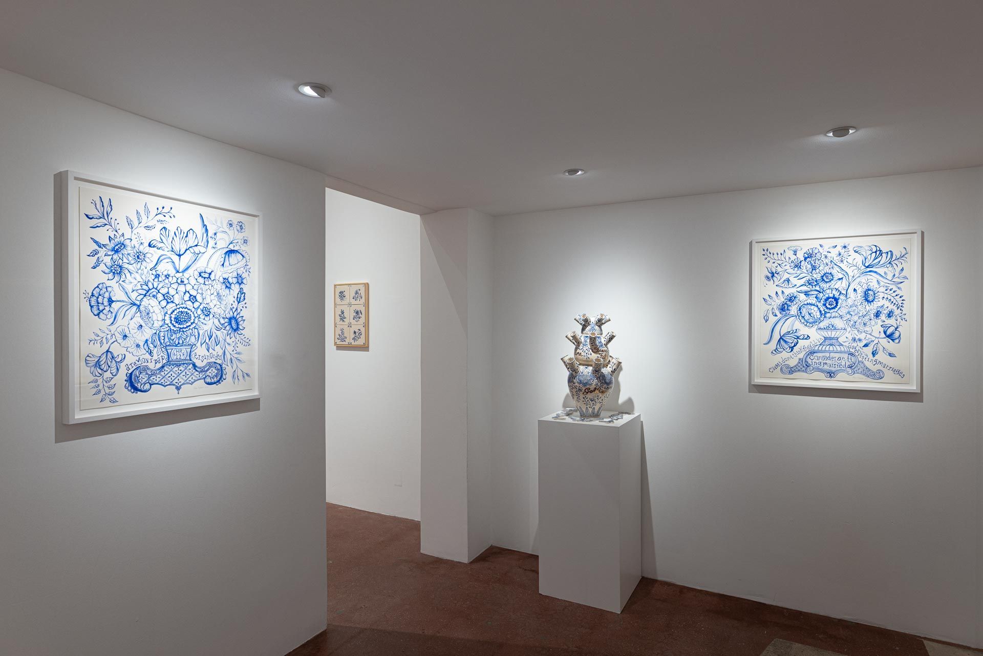 White-walled art gallery with two blue abstract wall pieces and a sculpture on a pedestal. Elyse Pignolet art exhibition at Track 16 East Hollywood gallery. Title, The Revolution Will Not Be Televised featuring ceramic works and drawings.