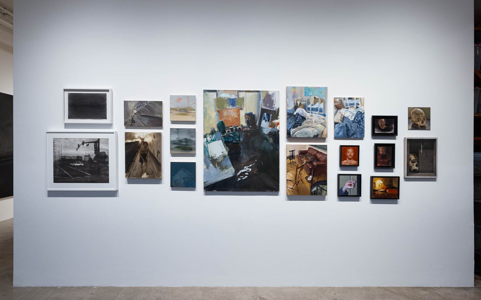 Straight-on view of a salon-style cluster of small paintings and framed works, with a larger painting at the center of the group. Installation view, Frank Ryan: Lived Perspective, Track 16.