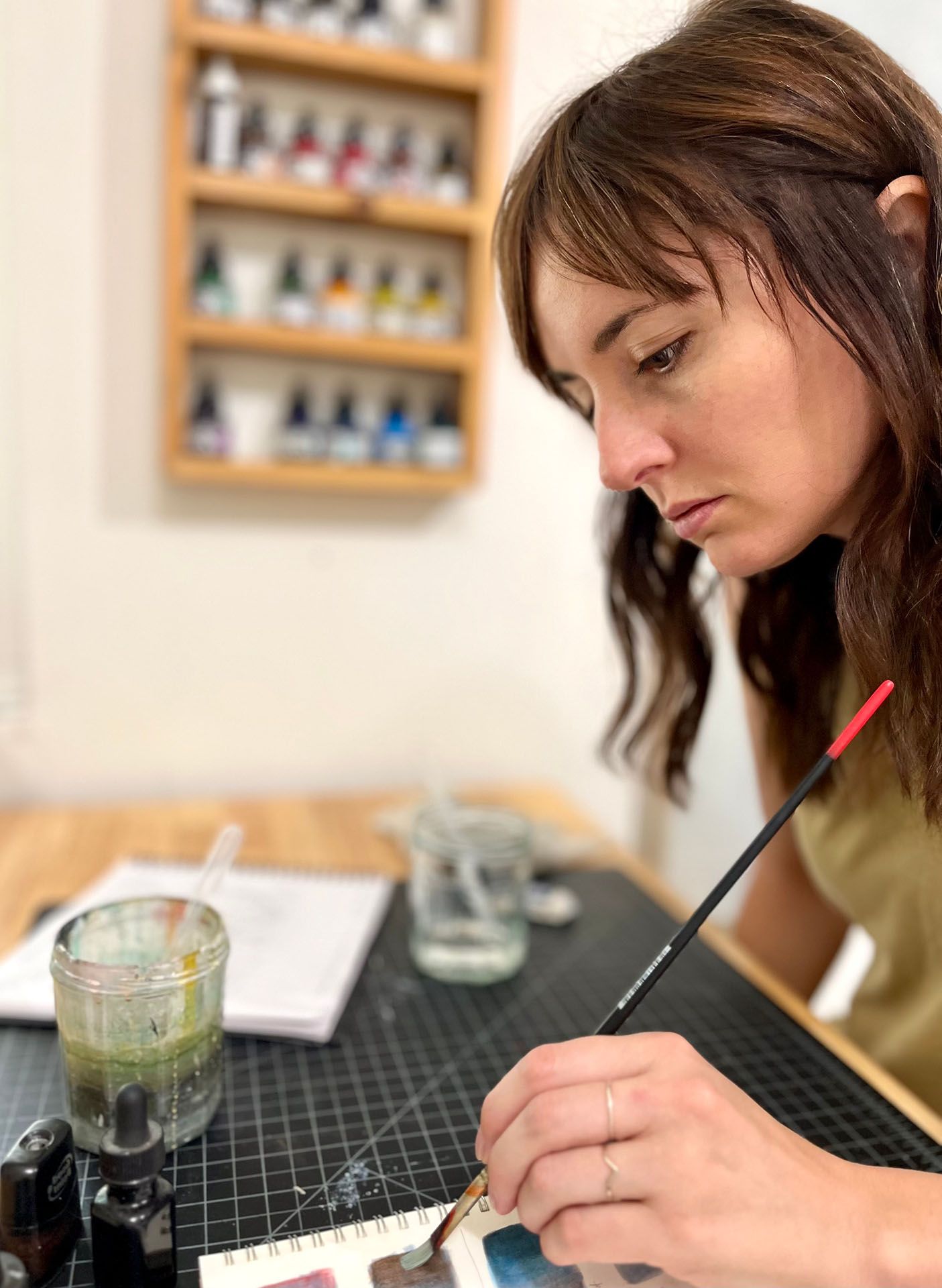 Roberta Gentry painting in a notebook at her desk.