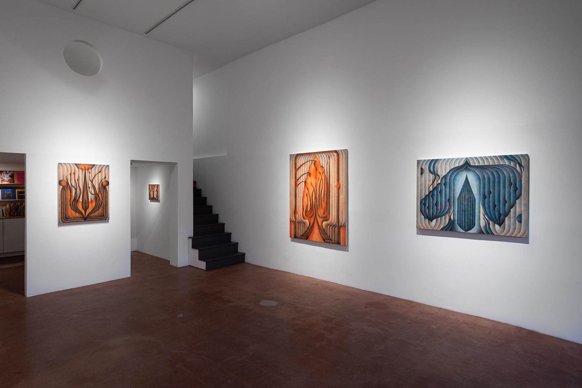 Orange and blue paintings on white walls, a dark staircase beyond a doorway. Installation view, Roberta Gentry: Blood Orange, Track 16, Los Angeles.