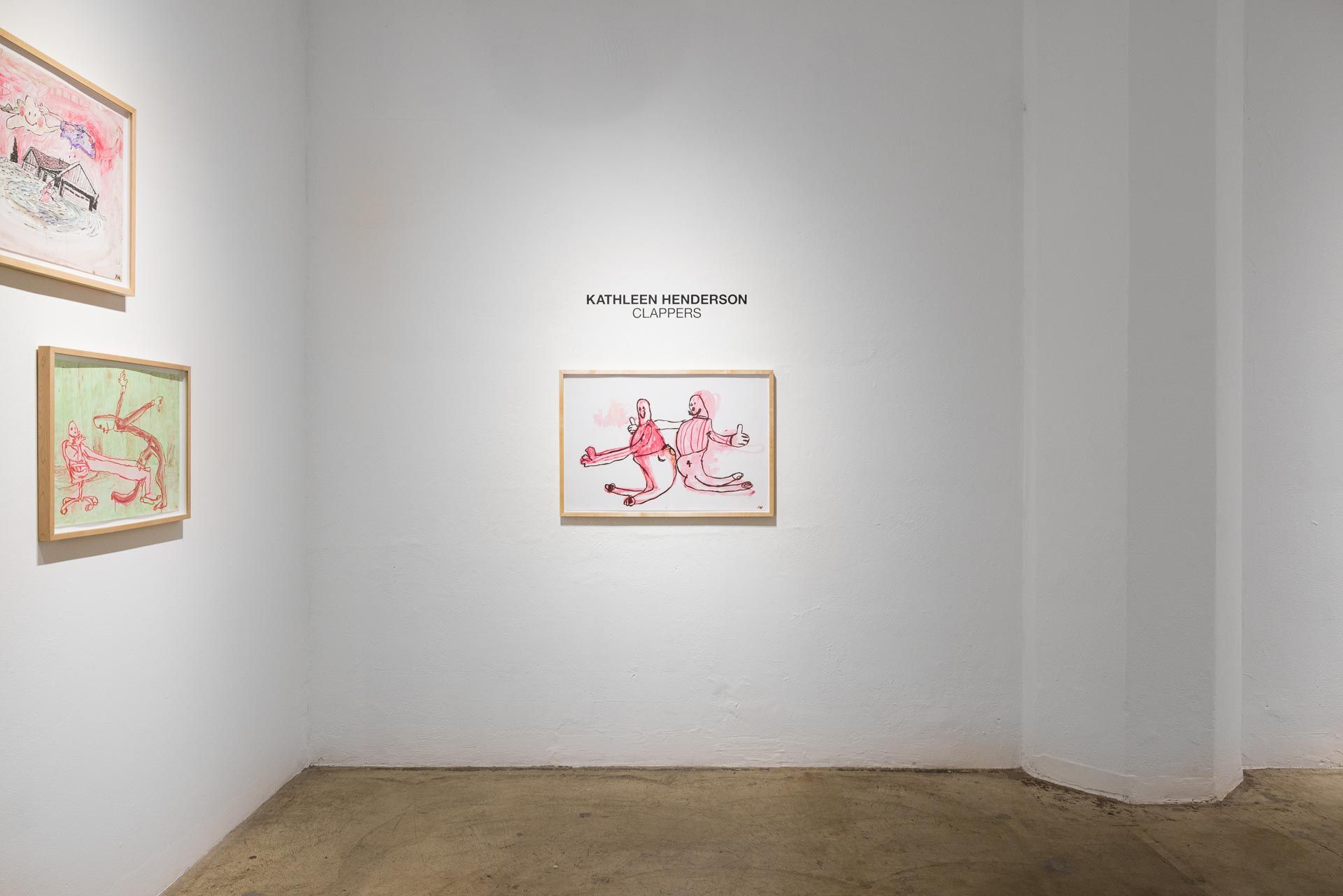 Framed drawing of pink ghost figures hanging beside the title wall text, a green drawing at left, in a white corner. Installation view, Kathleen Henderson: Clappers, Track 16.