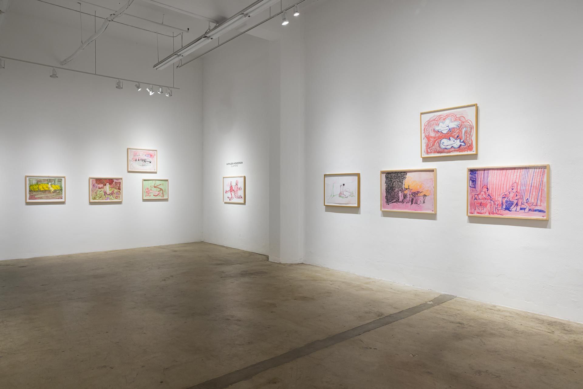 Framed pink and yellow drawings on white walls in a long room with track lighting and a concrete floor. Installation view, Kathleen Henderson: Clappers, Track 16.
