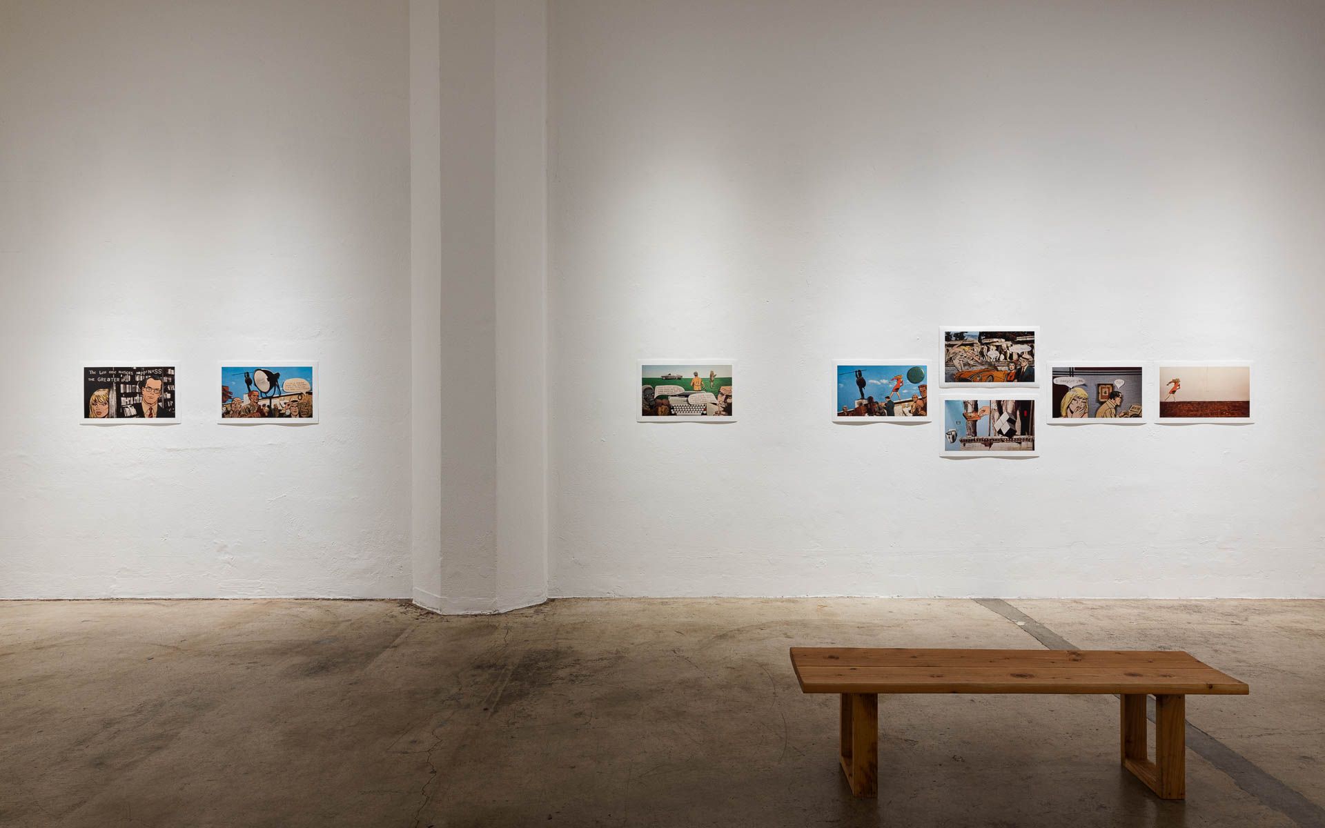 A wooden bench is sitting in a room with paintings on the wall.