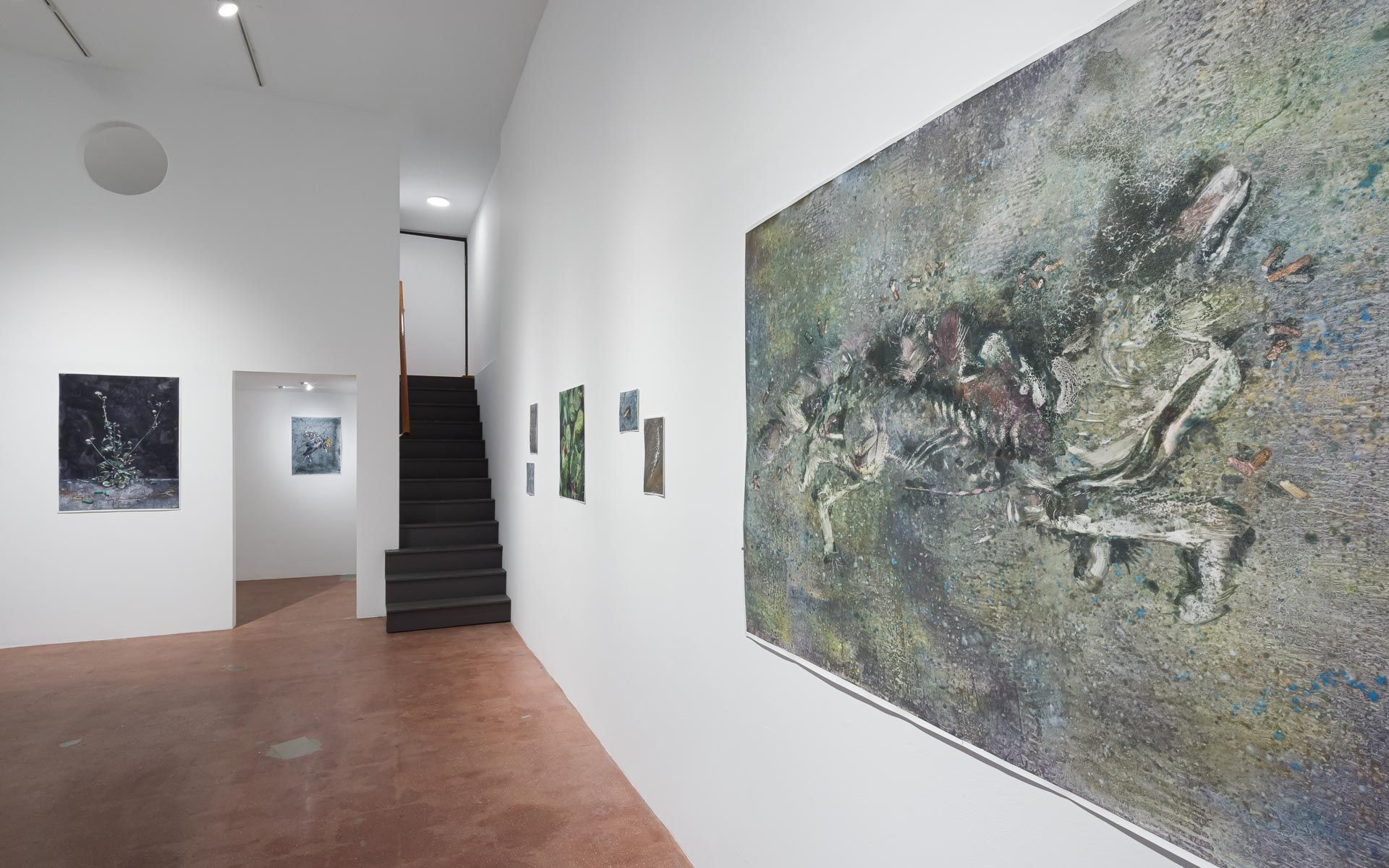Large mossy gray-green painting with a sprawled animal form on the right wall, small dark and green works beside a staircase. Installation view, Molly Segal: As We Grind Our Teeth To Dust, Track 16.