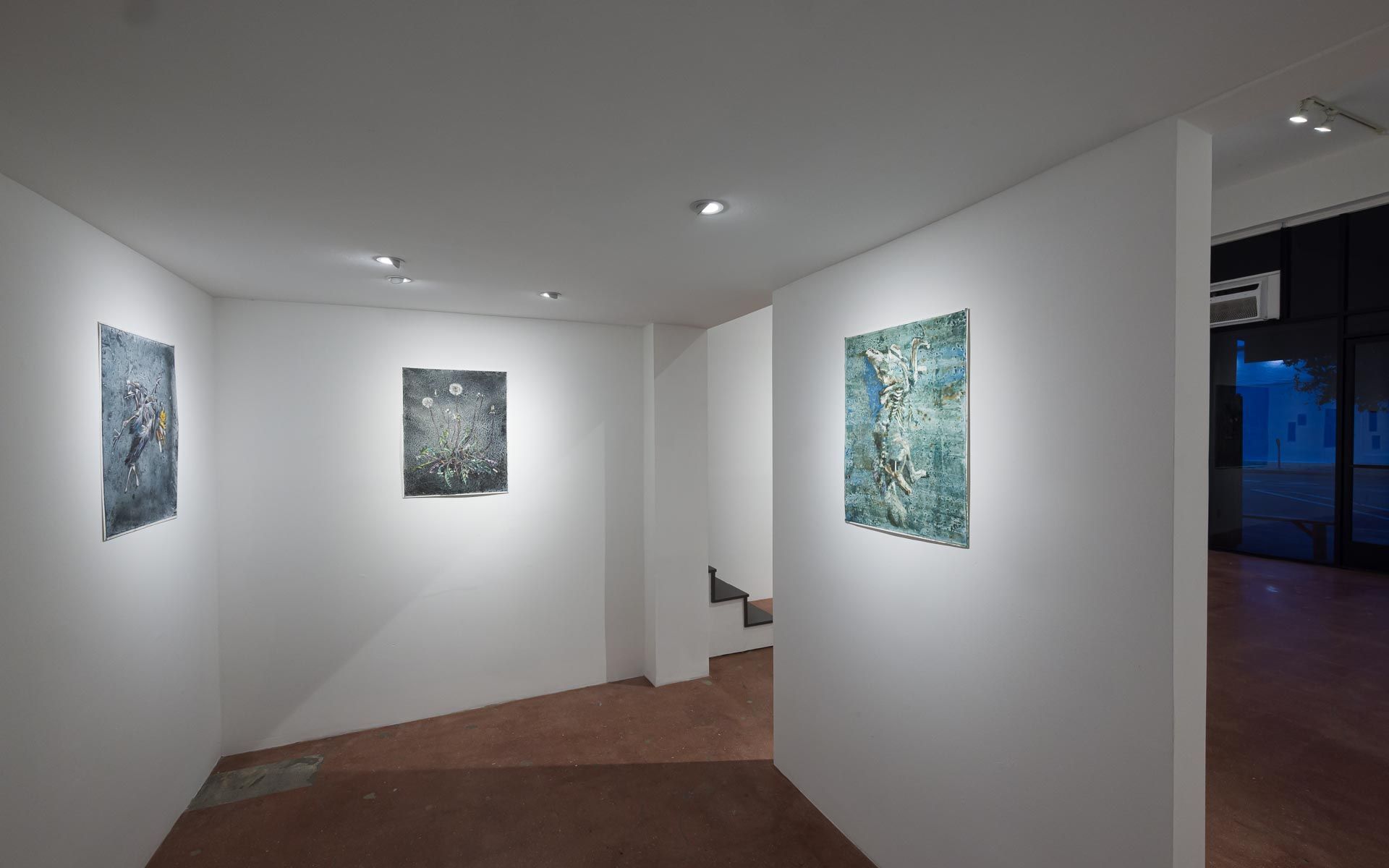 Blue-green textured painting on a freestanding wall at center, a large dark gray painting at right and small works down a side hall. Installation view, Molly Segal: As We Grind Our Teeth To Dust, Track 16.