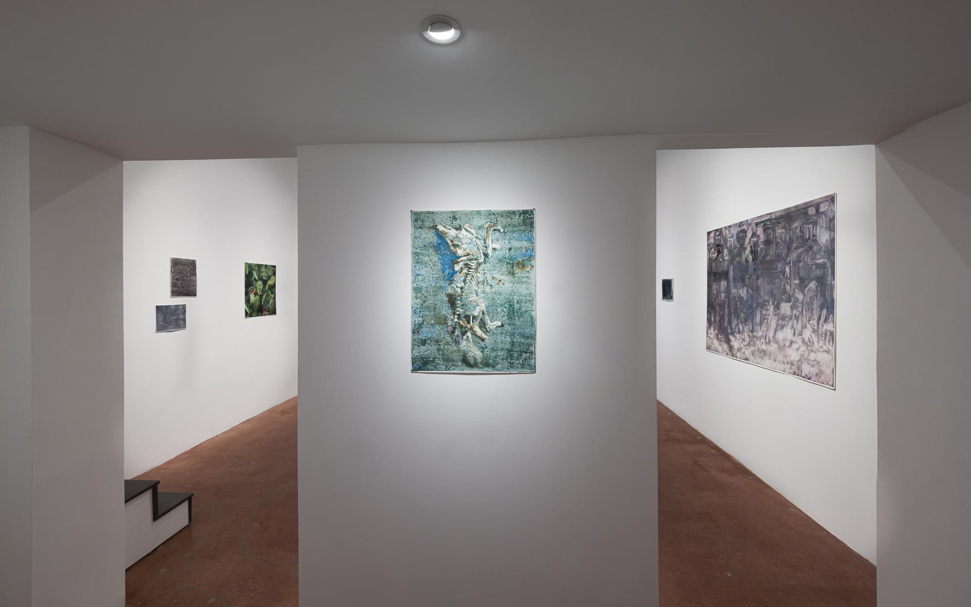Blue-green textured painting on a freestanding wall at center, a large dark gray painting at right and small works down a side hall. Installation view, Molly Segal: As We Grind Our Teeth To Dust, Track 16.