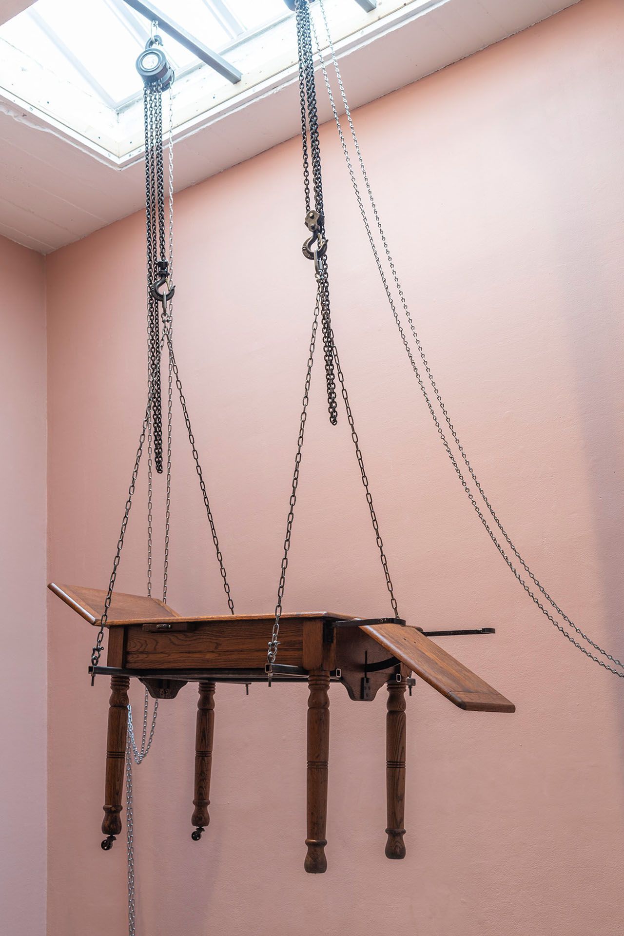 A wooden table is hanging from chains from the ceiling