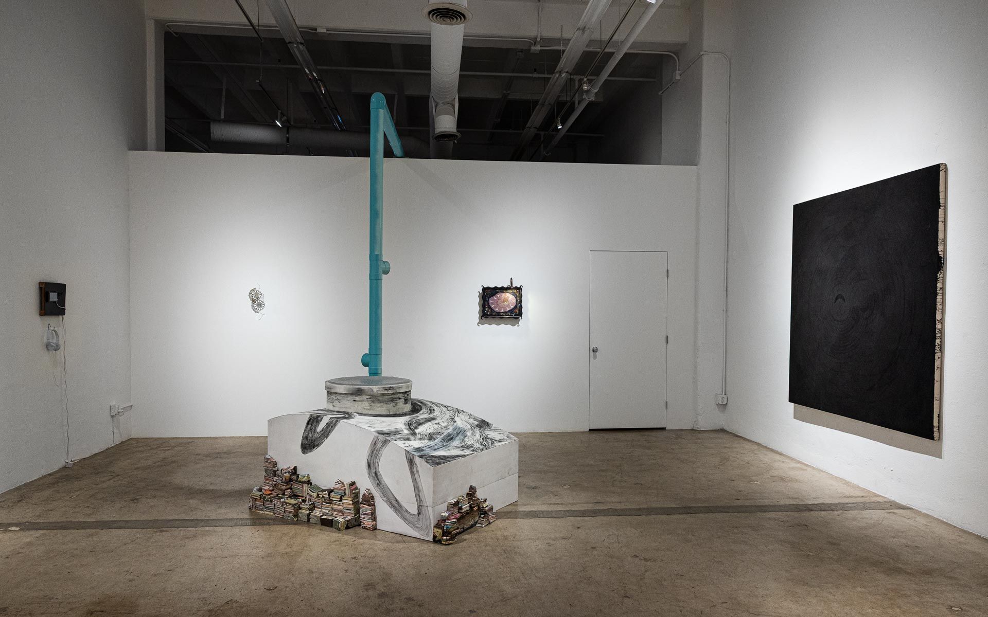 Art gallery room with a central sculpture, white walls, and two framed artworks on display. Praise the Dying Beauty art exhibition at Track 16 Downtown Los Angeles gallery. Curated by Galia Linn featuring sculpture, paintings and drawings. 