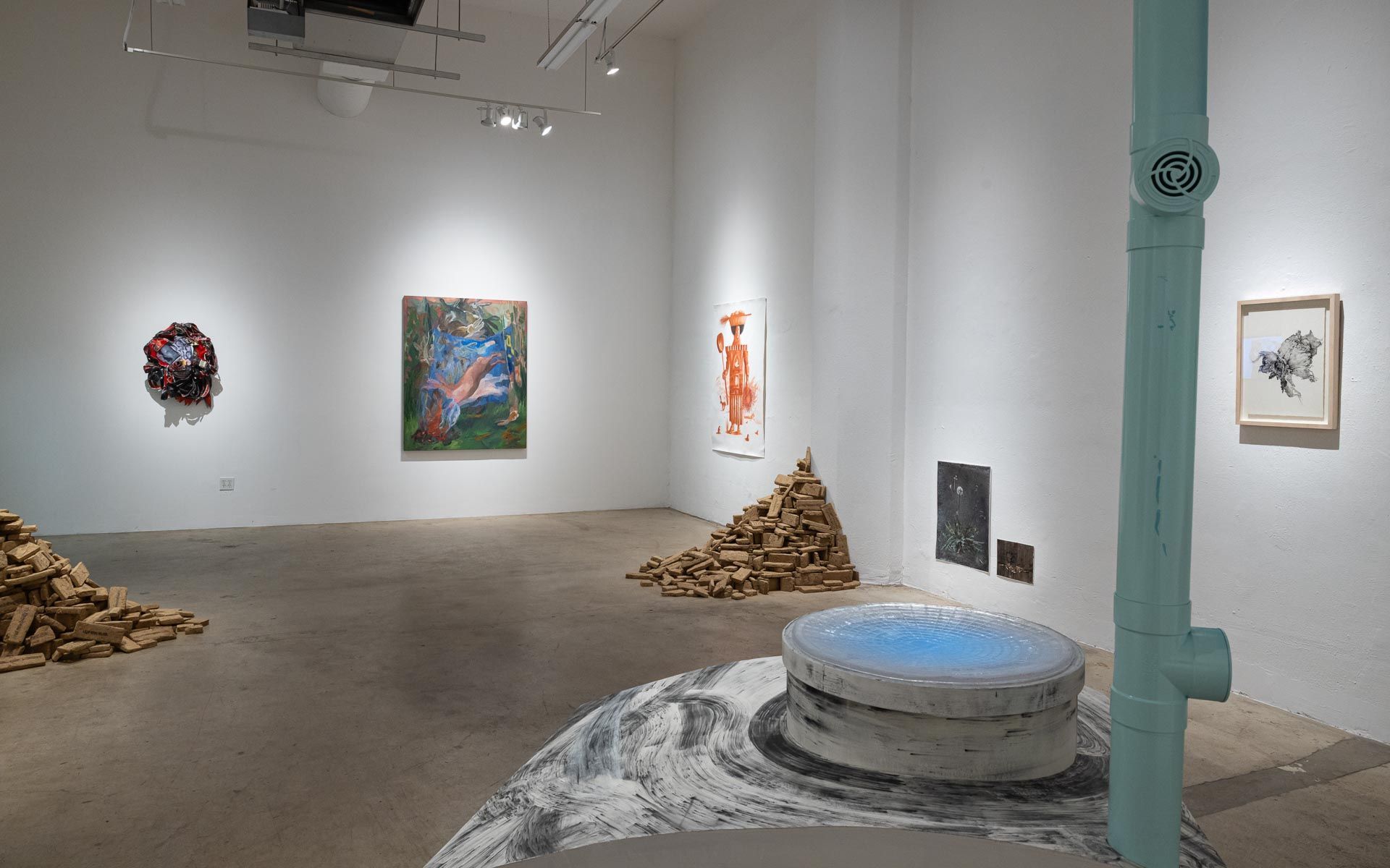 Art gallery interior with abstract paintings on white walls and a staircase in the back. Praise the Dying Beauty art exhibition at Track 16 Downtown Los Angeles gallery. Curated by Galia Linn featuring sculpture, paintings and drawings. 