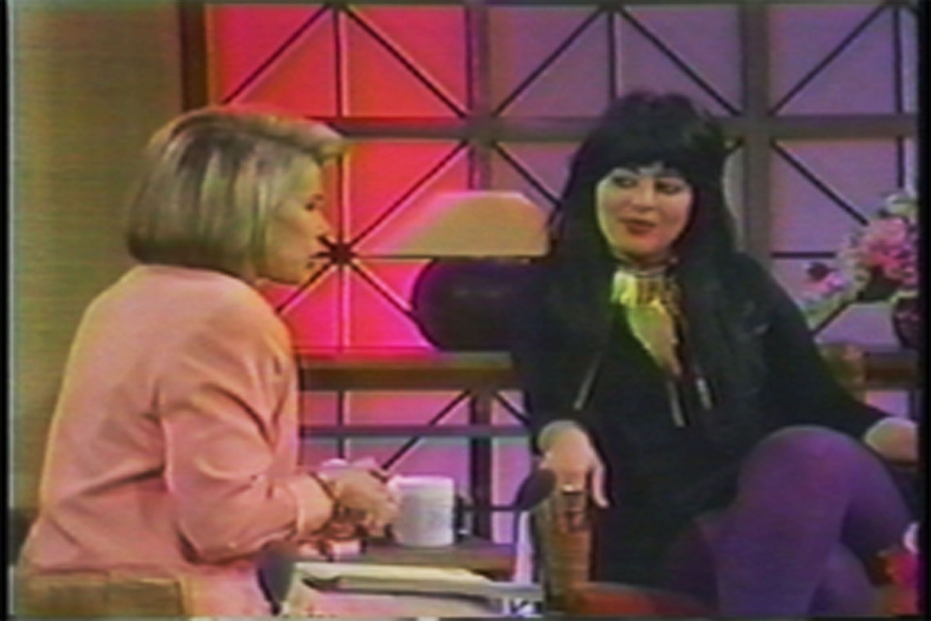 Two women are sitting at a table talking to each other