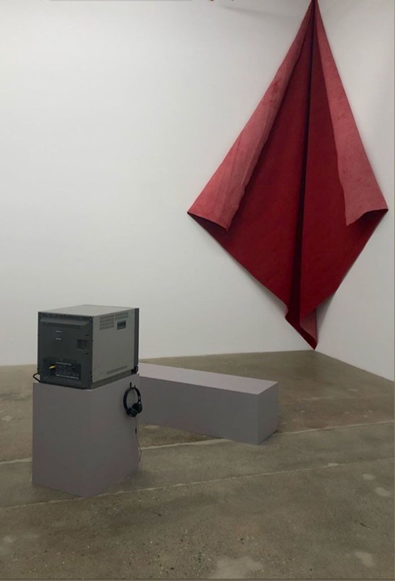 A corner of a room with a large red cloth hanging on the wall