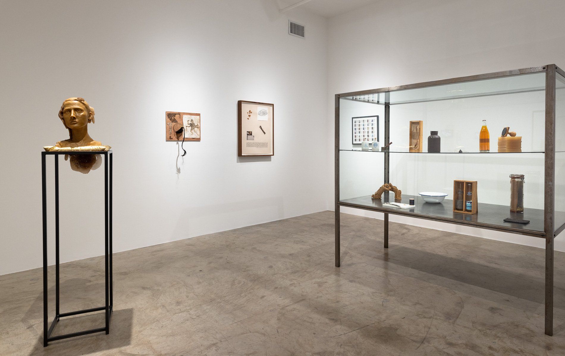 A room with a glass display case and a statue on a pedestal.