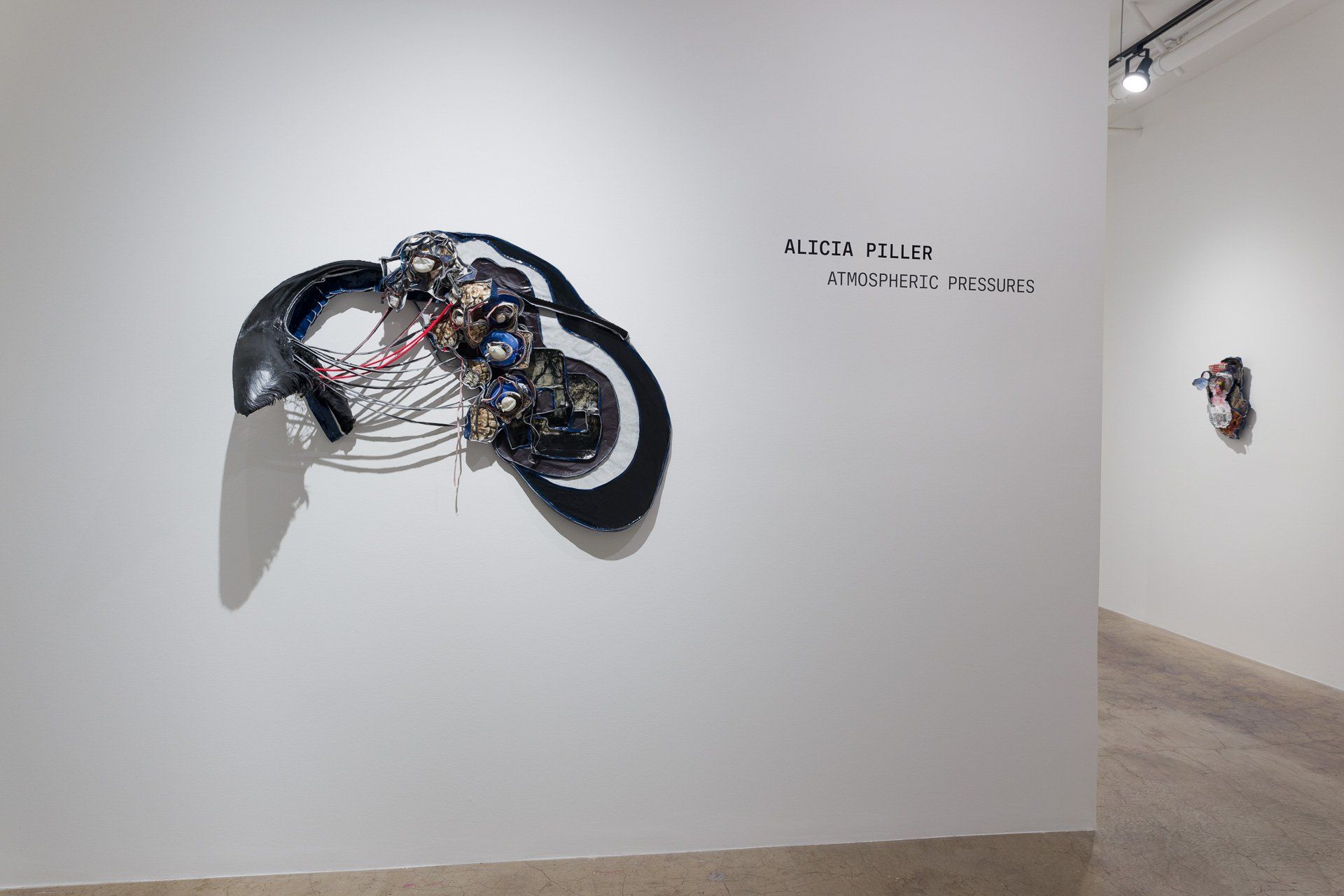 A sculpture is hanging on a white wall in Track 16 Gallery.