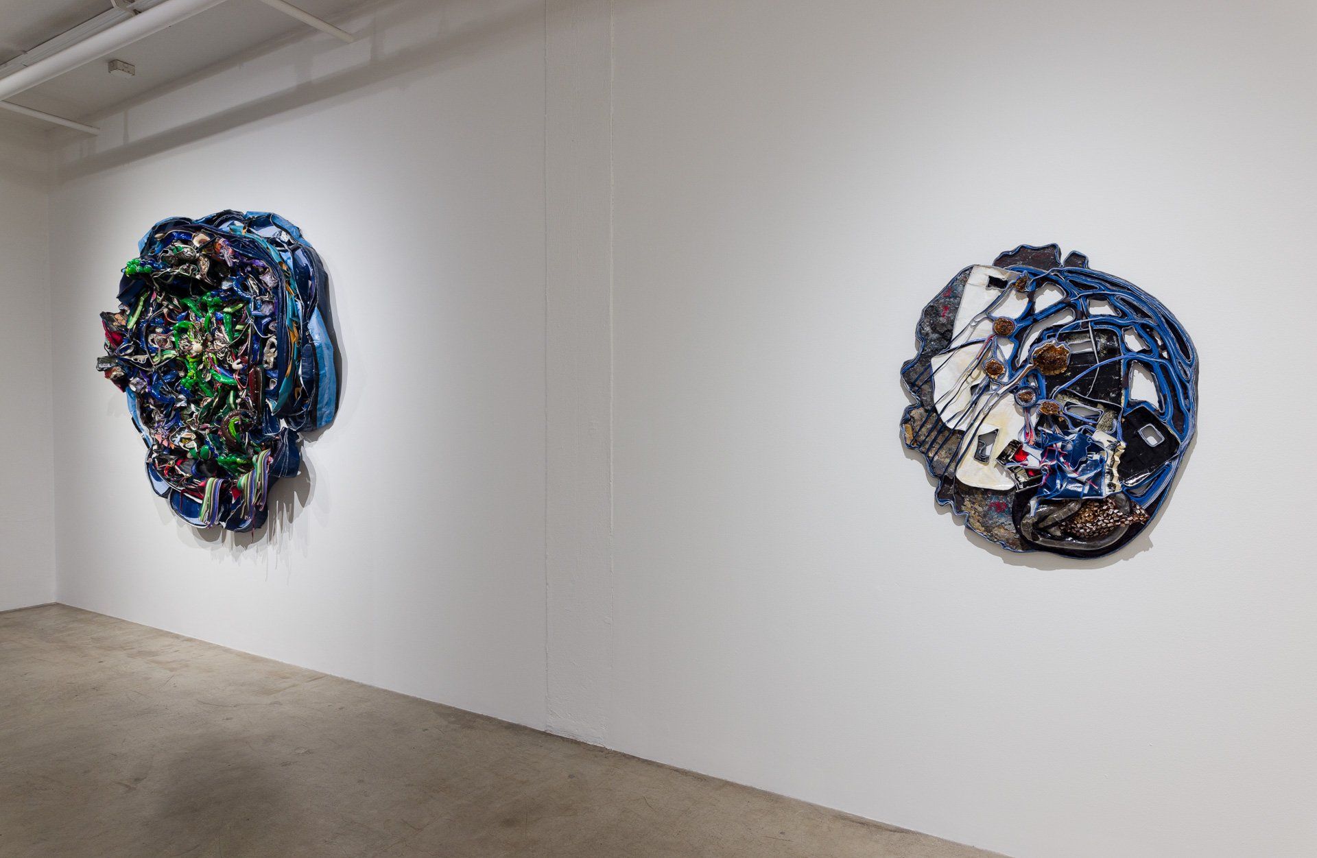 Two paintings are hanging on a white wall in a room.