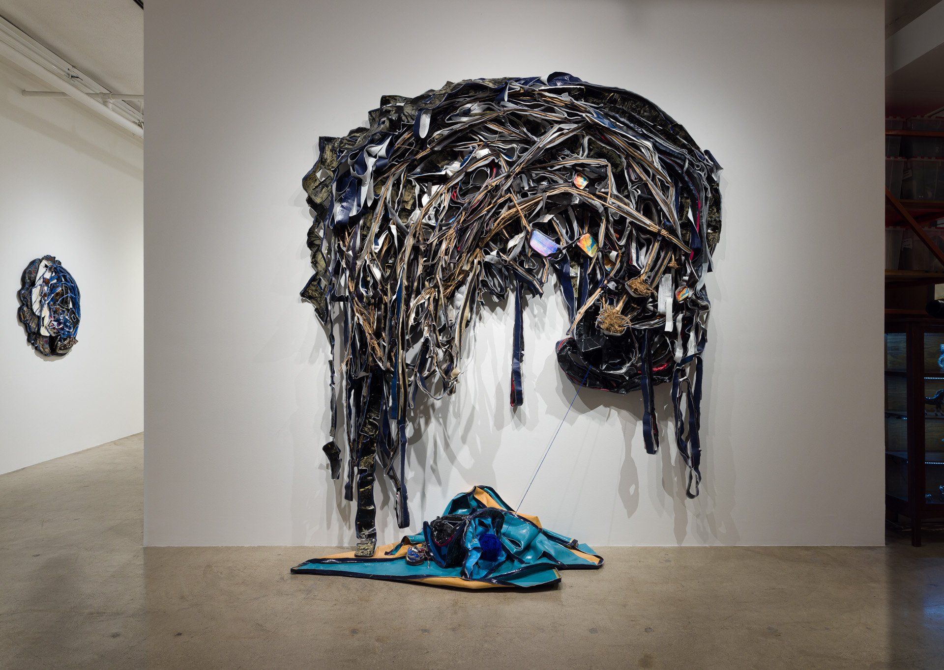 A large sculpture is hanging on a wall in Track 16 Gallery.