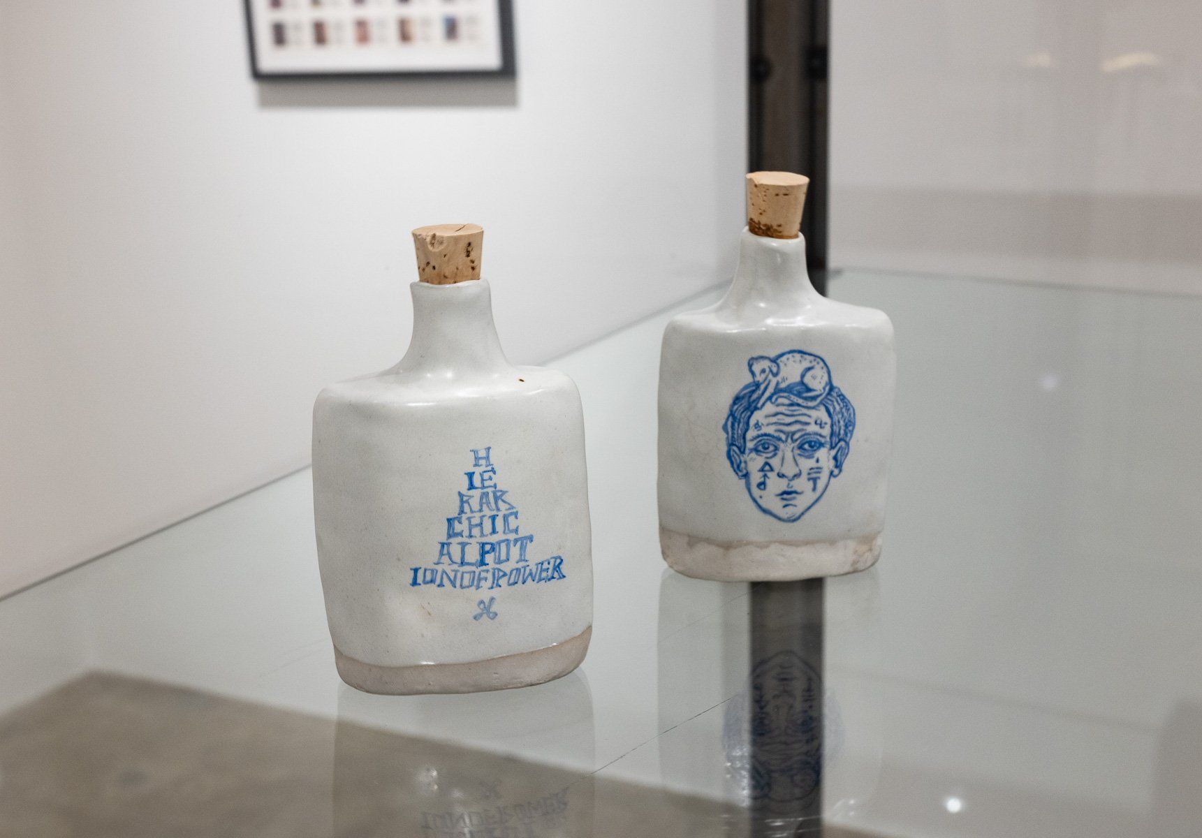 Two ceramic bottles with corks are sitting on a glass table.