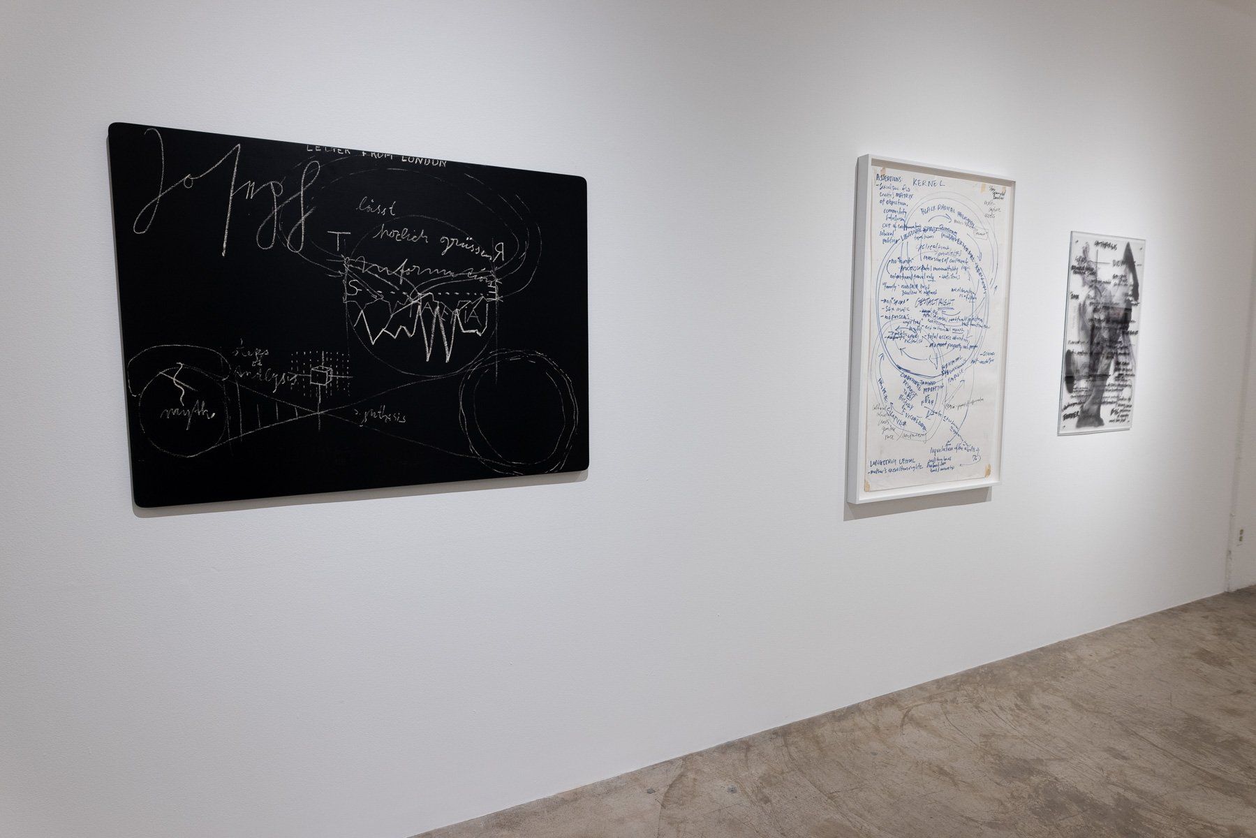 Three paintings are hanging on a white wall in Track 16 Gallery.