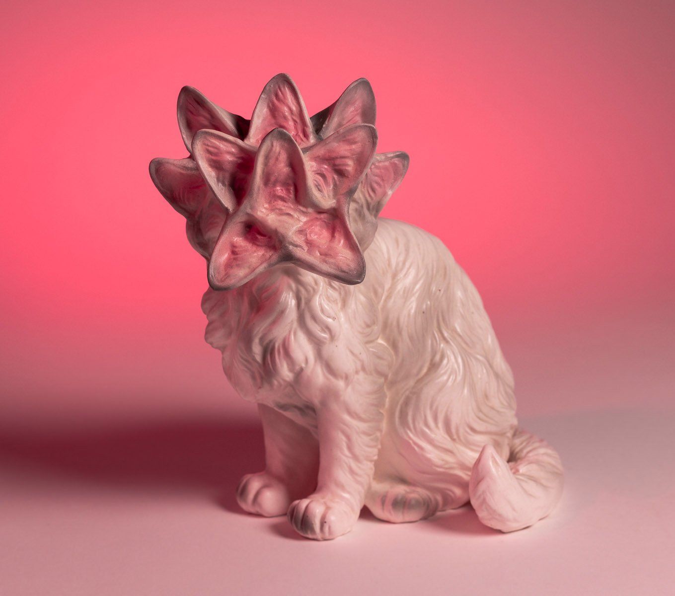 A statue of a cat with a flower on its head.