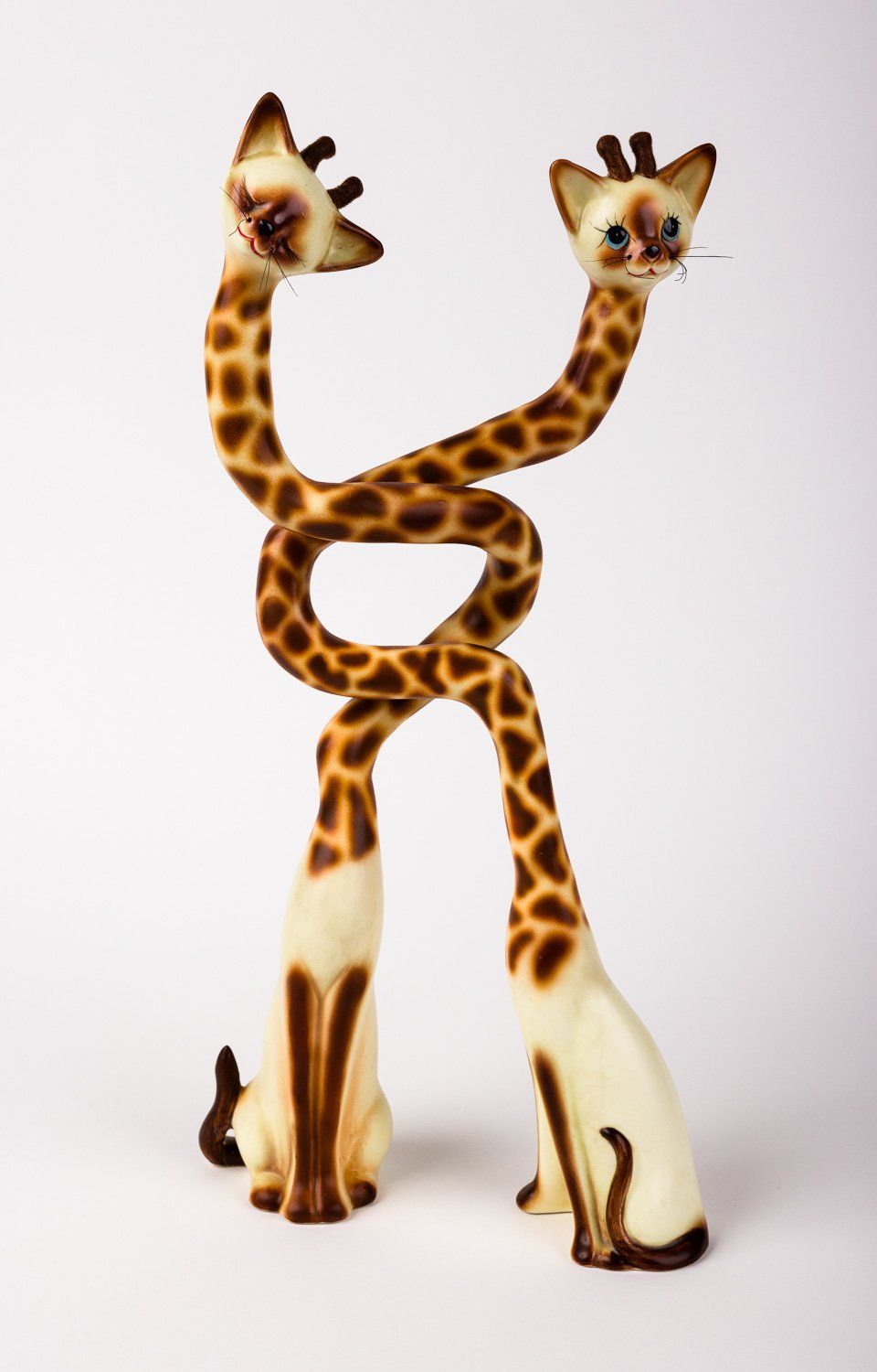 Two giraffes are standing next to each other on a white surface.