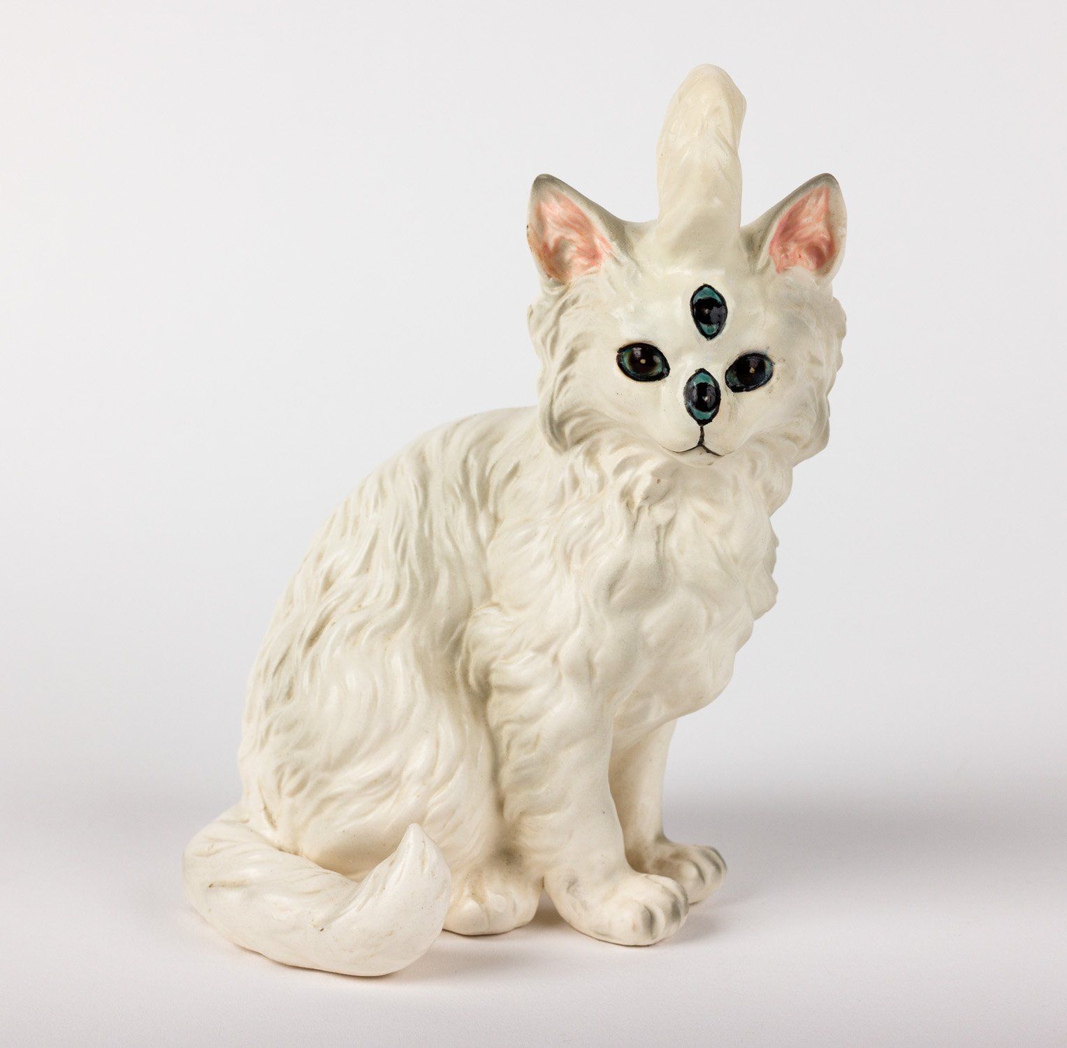 A white cat with three eyes and a horn on its head