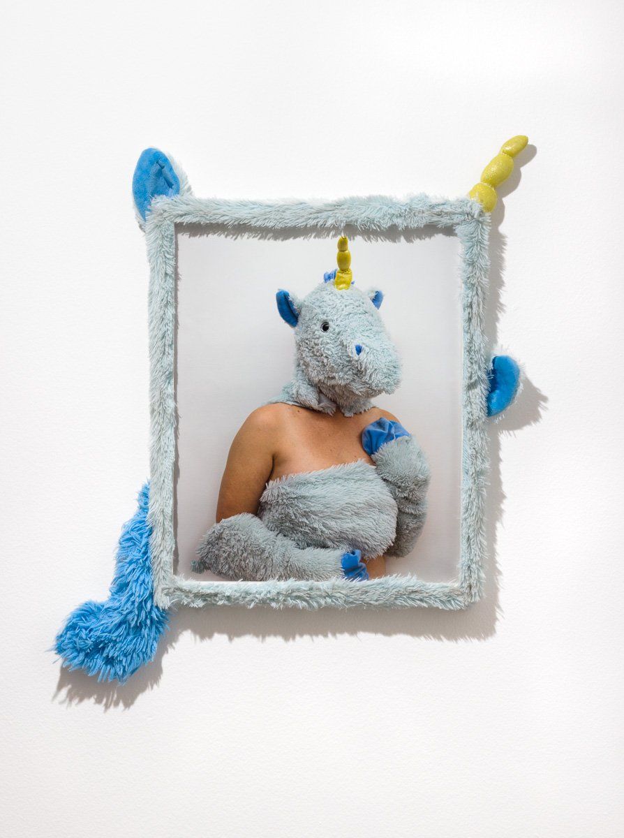 A woman in a unicorn costume is in a picture frame.