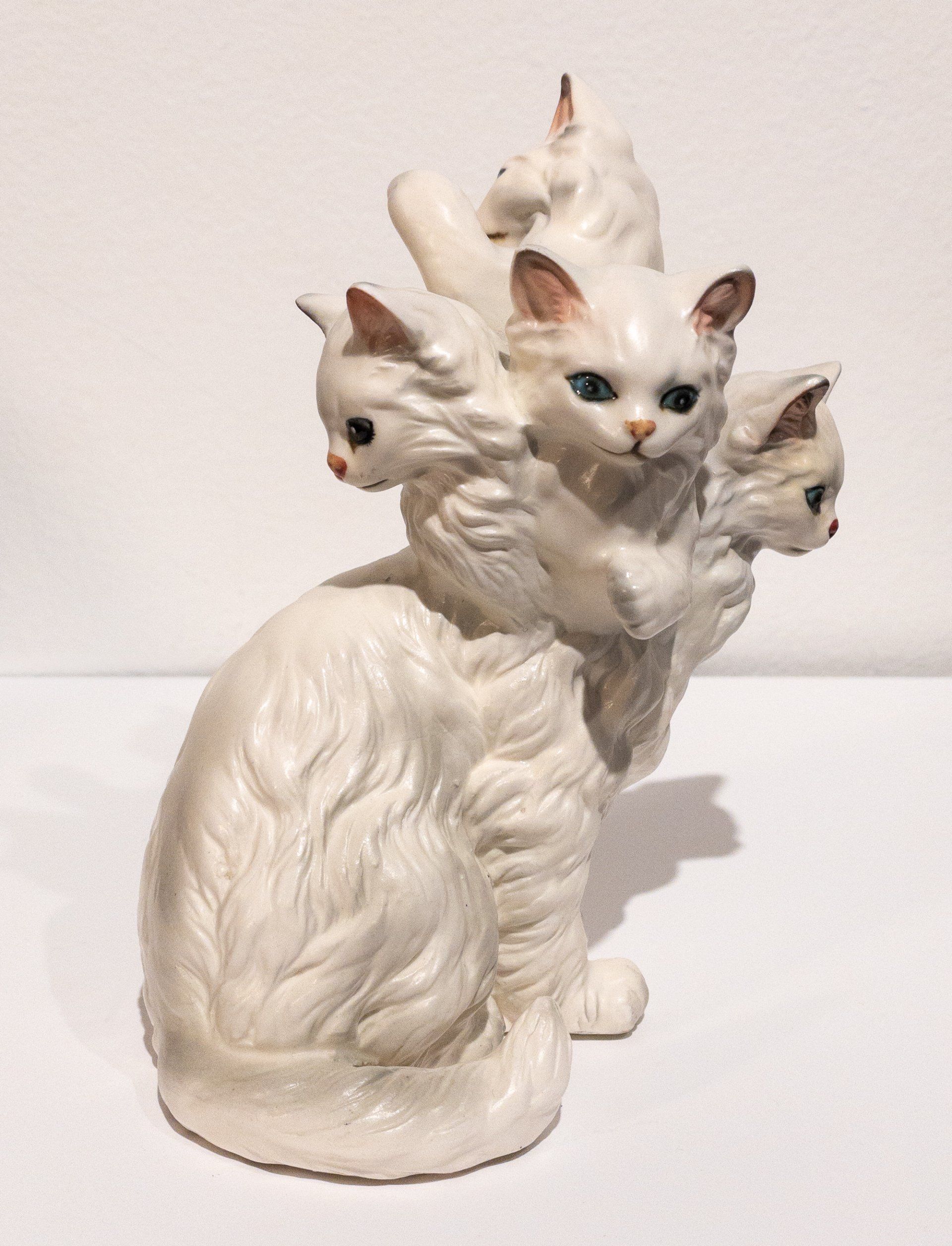 A white statue of a cat with three kittens on its back