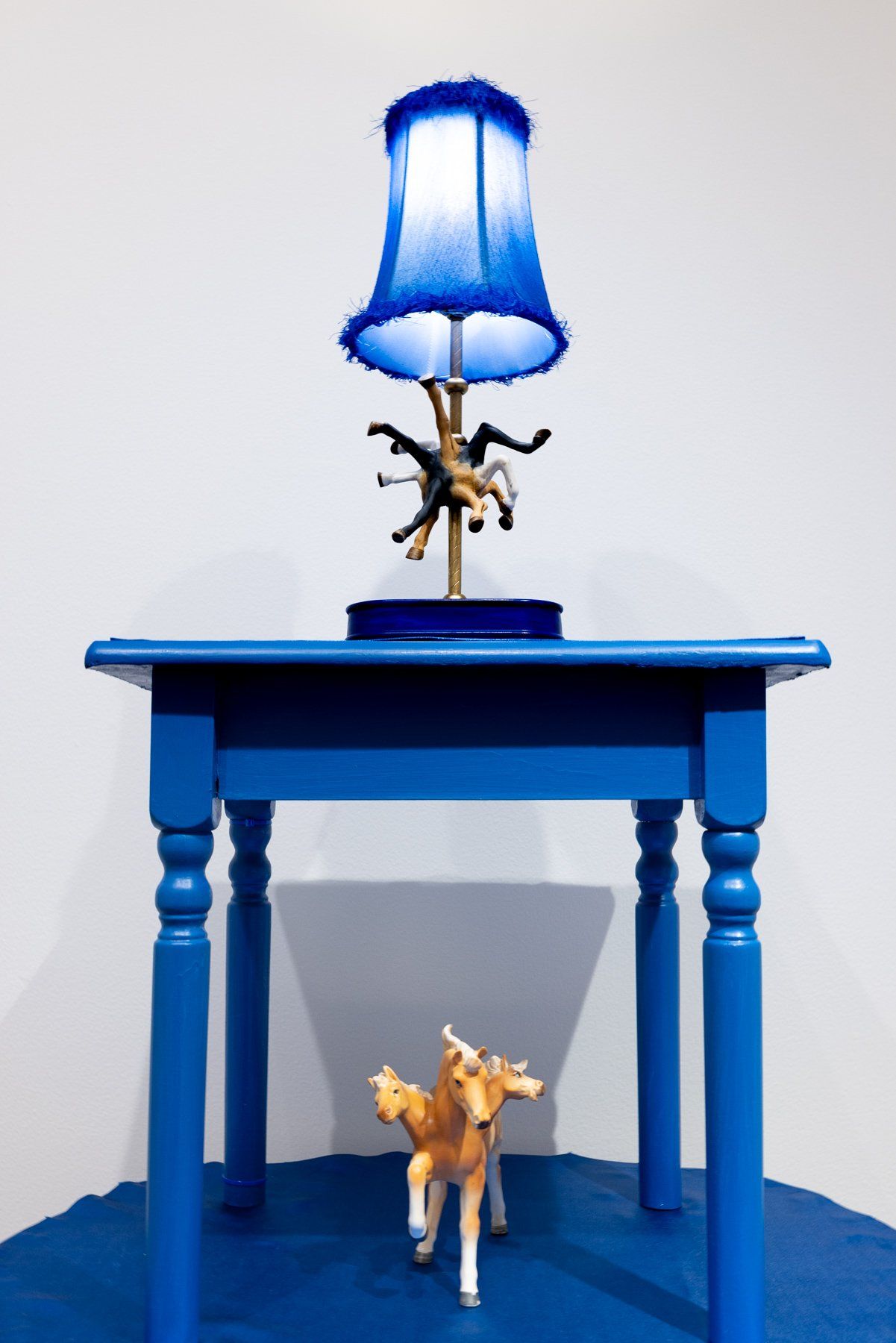 A blue table with a lamp and a toy horse on it