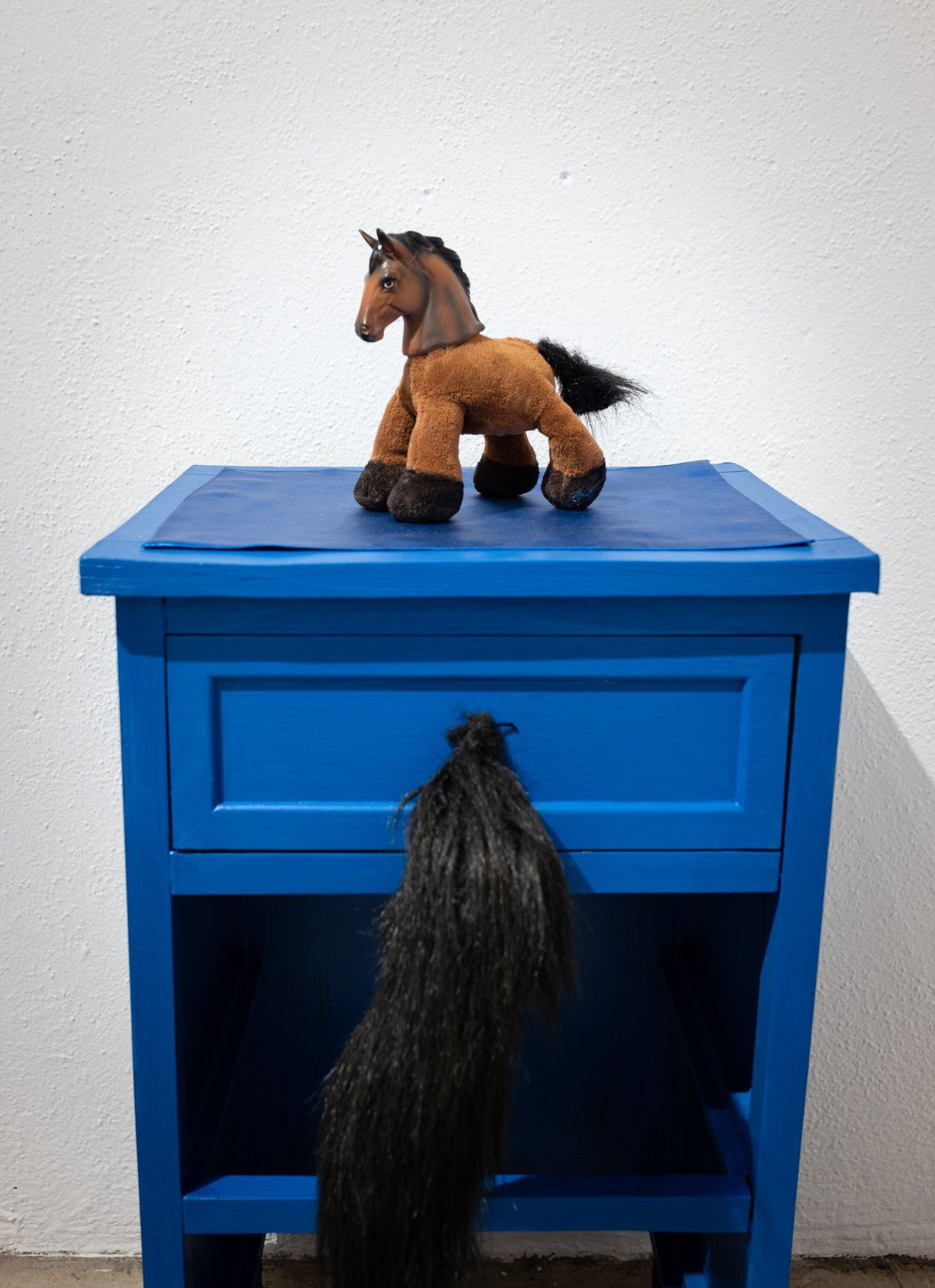 A stuffed horse is sitting on top of a blue nightstand