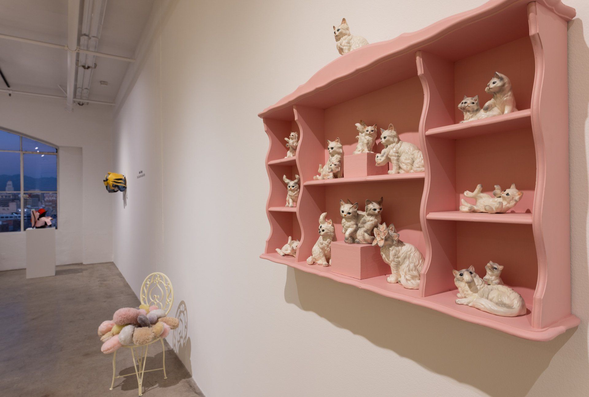 A pink shelf with ceramic animals on it in a room.