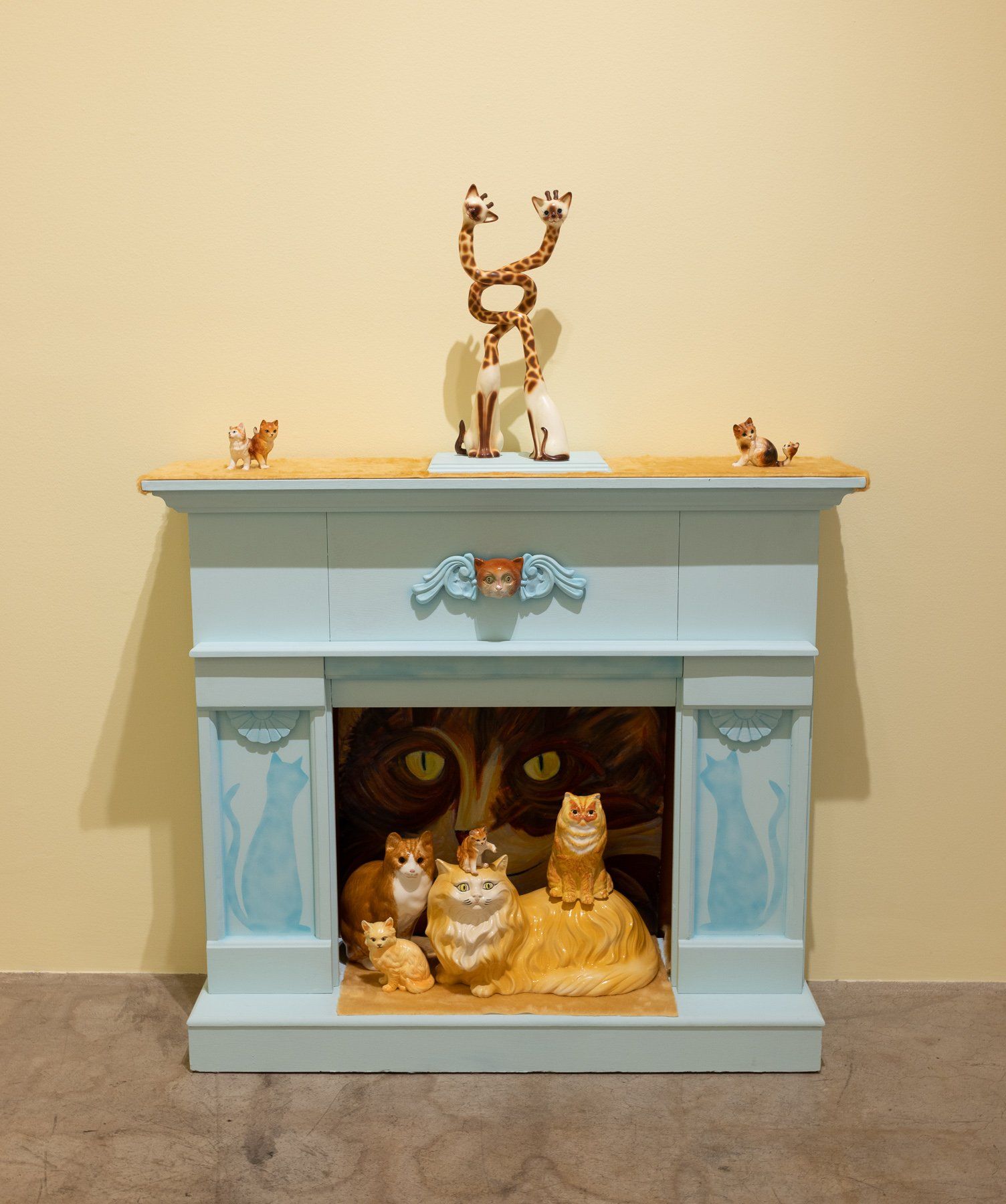 A blue fireplace with cats and a statue on top