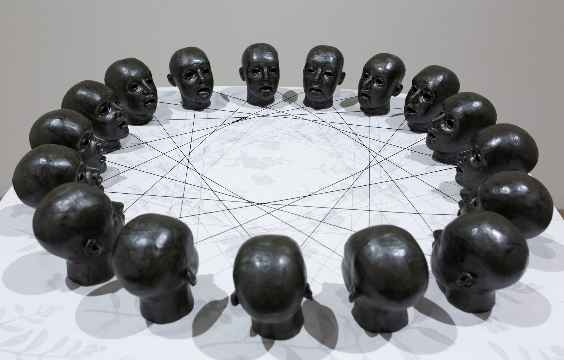 A display of heads in a circle with lines connecting them on a white table.