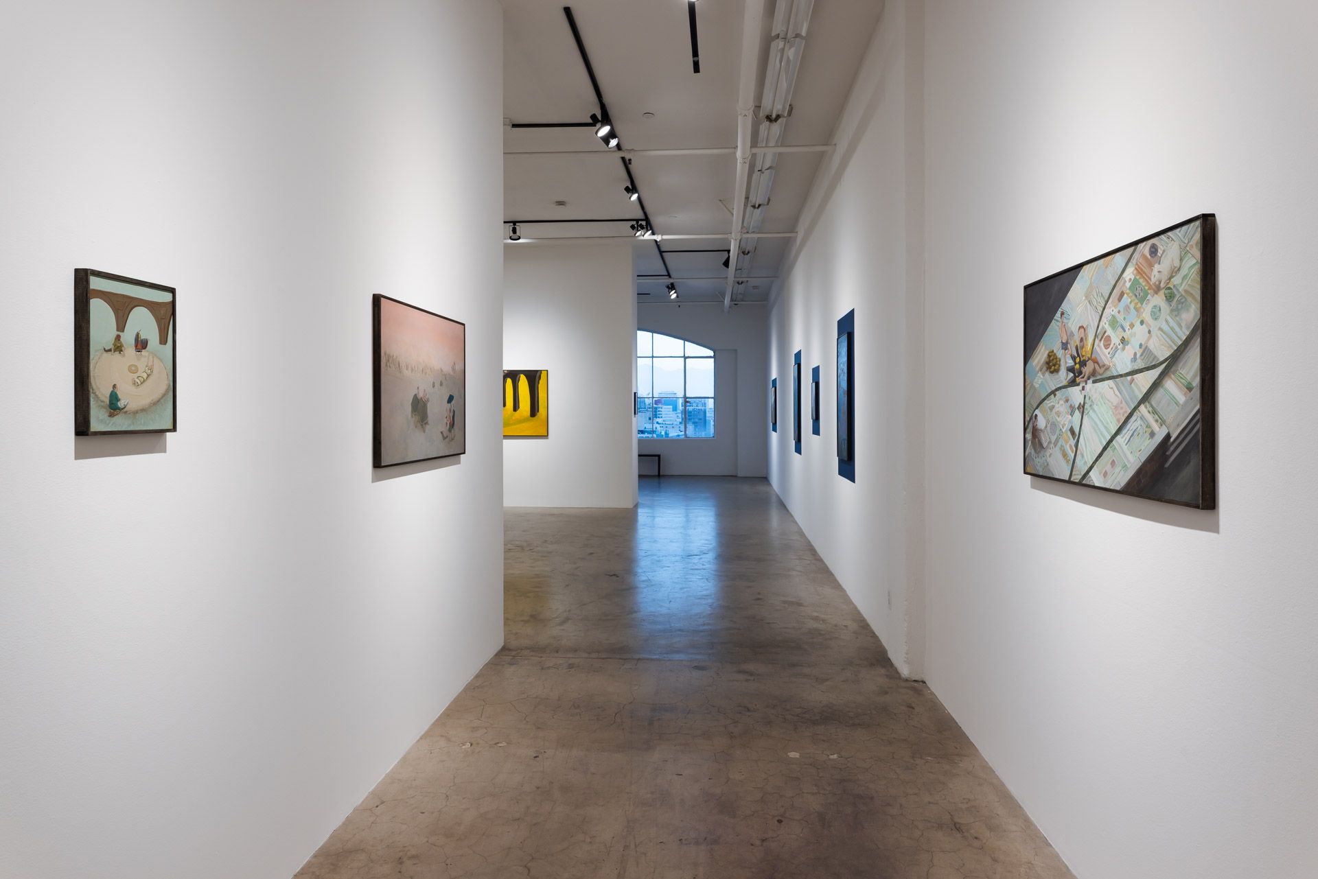 A long hallway in a museum with paintings on the wall.