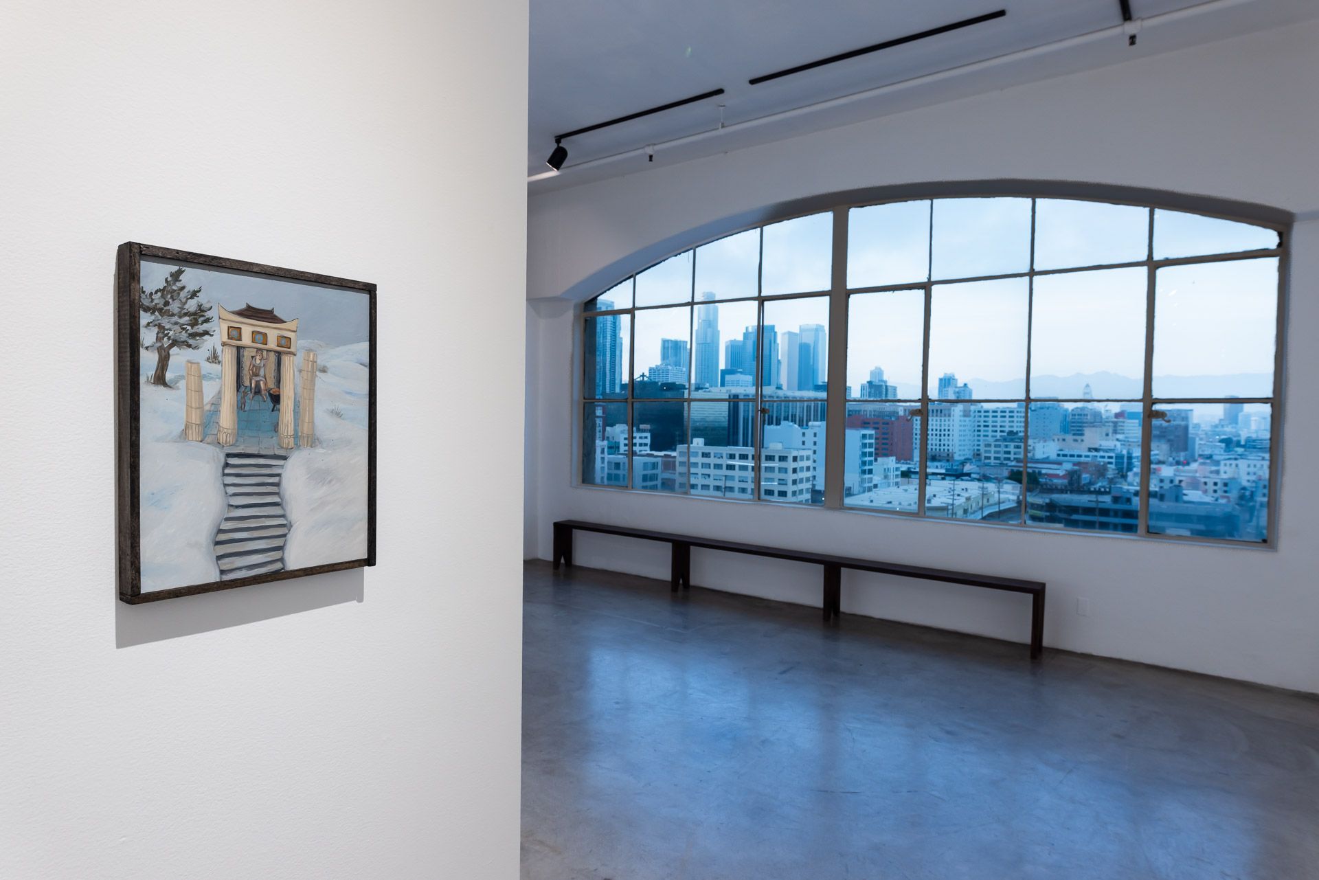 An empty room with a large window and a painting on the wall.