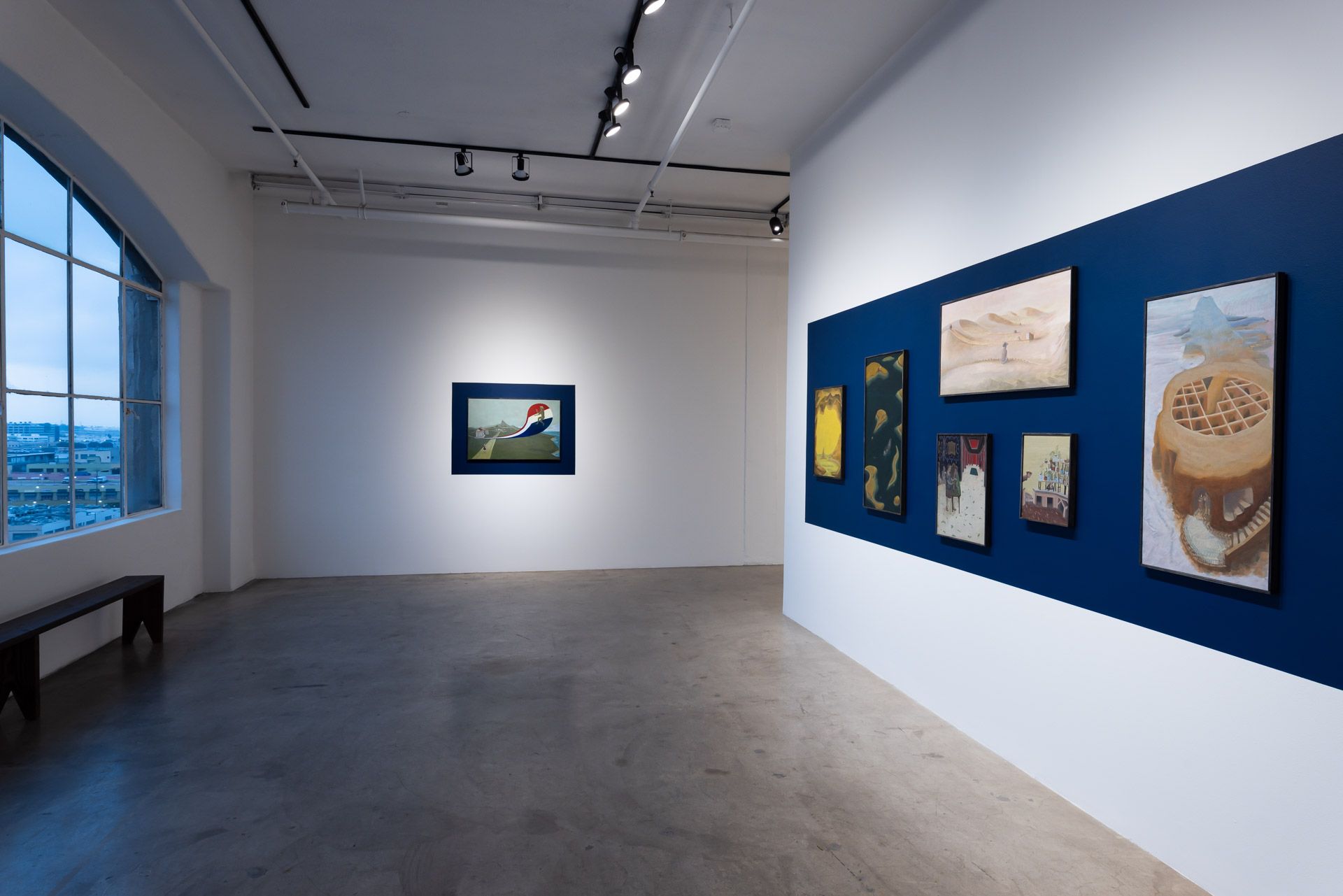 A large empty room with a blue wall and paintings on it.