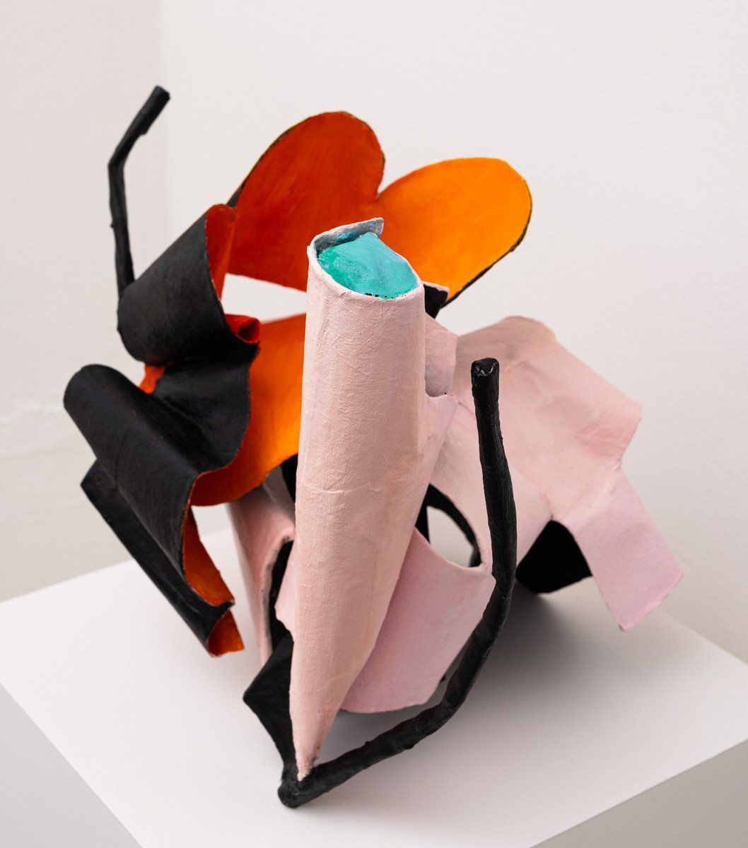 A colorful sculpture is sitting on a white shelf